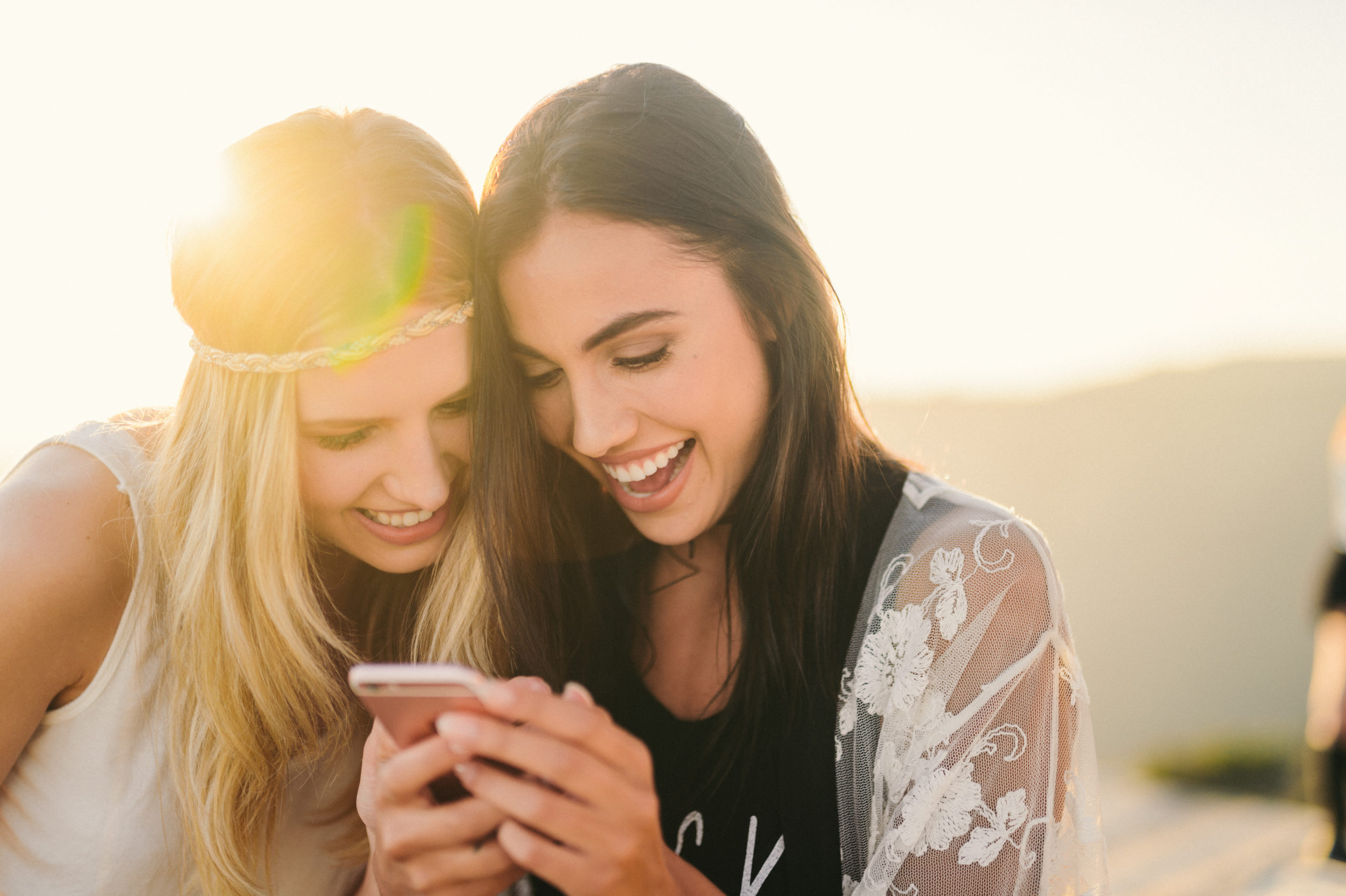 Two women looking at something on a cellphone smiling