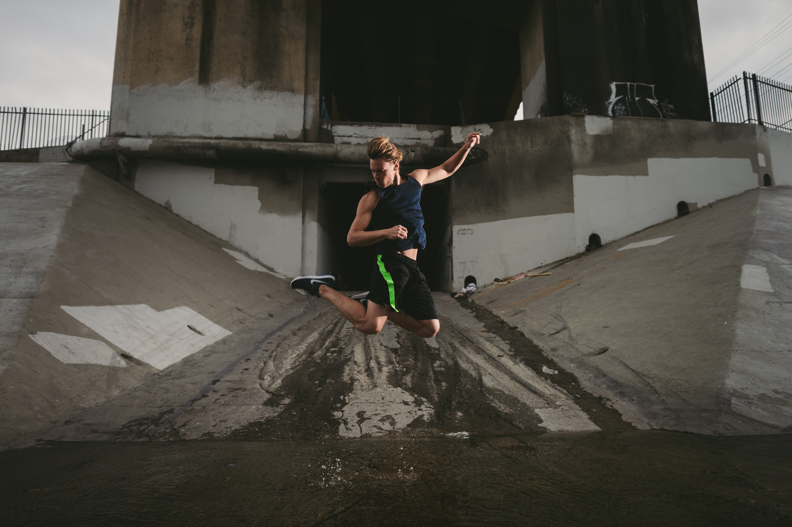 Man jumping in the air in front of a culvert