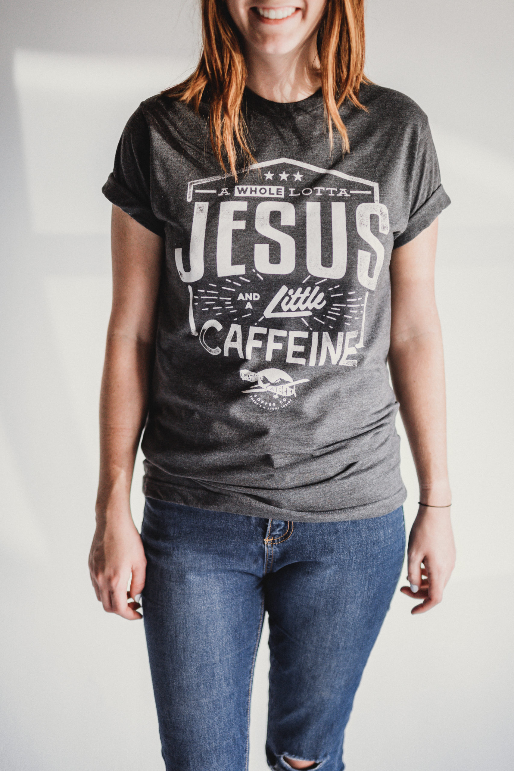 JSM Woman wearing a gray t shirt that says A Whole Lotta Jesus and a Little Caffeine from Crazy Faith