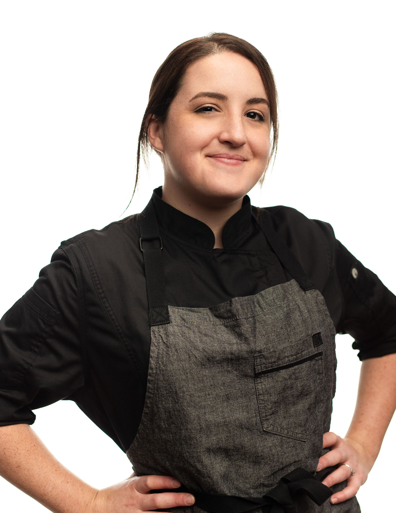 KES Headshot of woman with short brown hair wearing a gray chef outfit smiling and posing for the camera