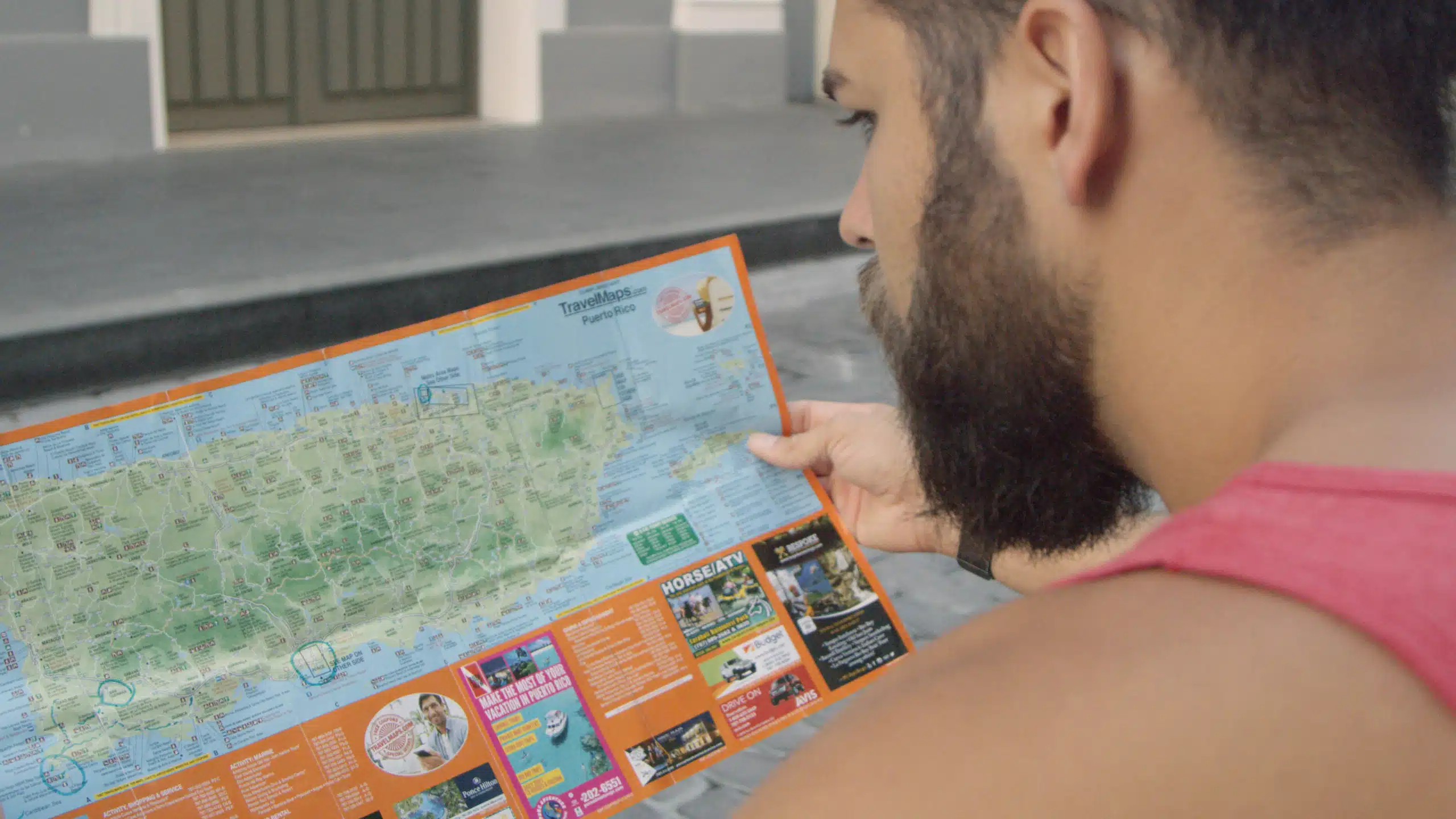Black Mile Blackmile Closeup look over the shoulder of a man with a bushy beard looking at a map of Puerto Rico island