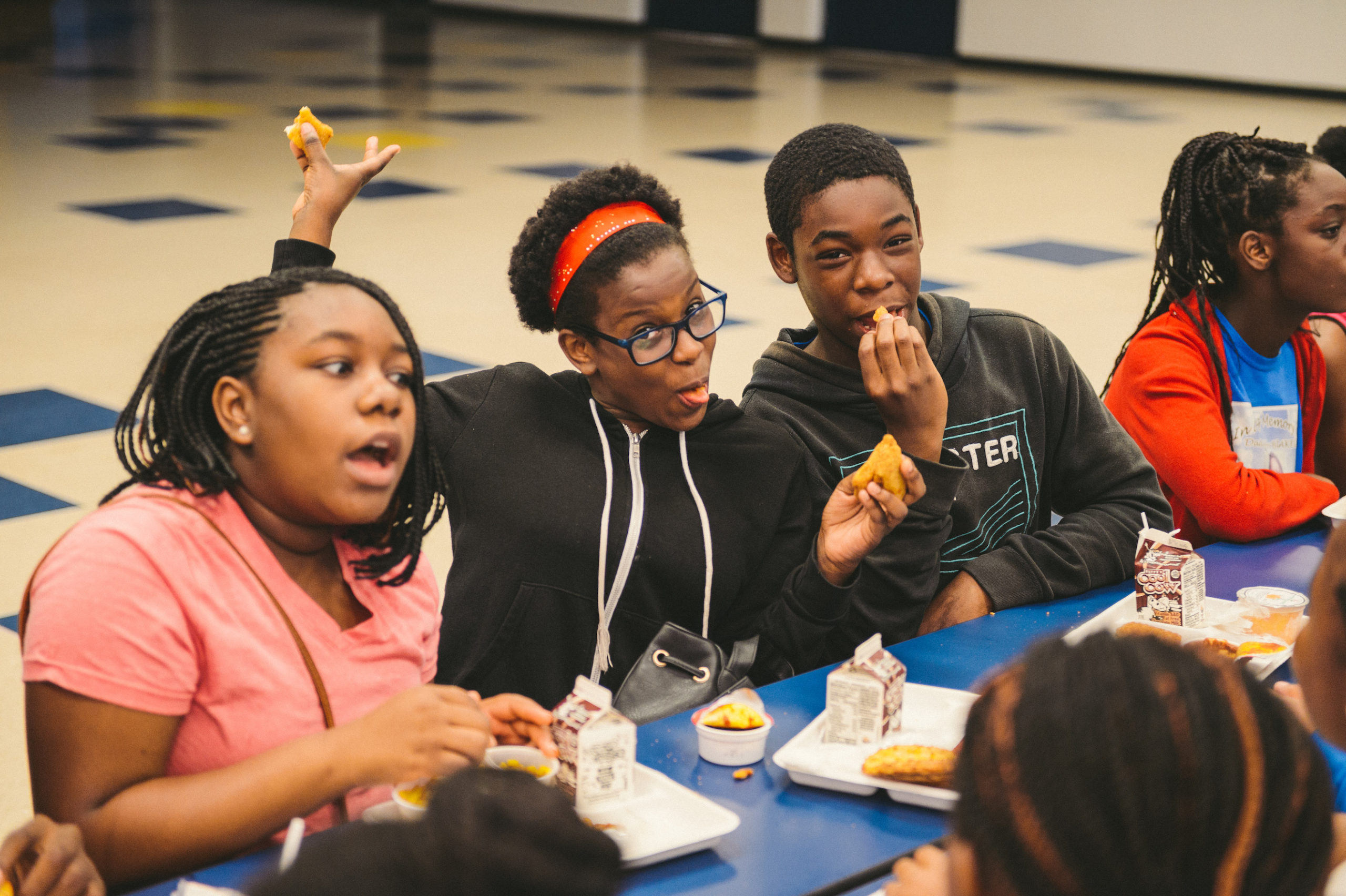 Group of African American young adults enjoying lunch in the cafeteria