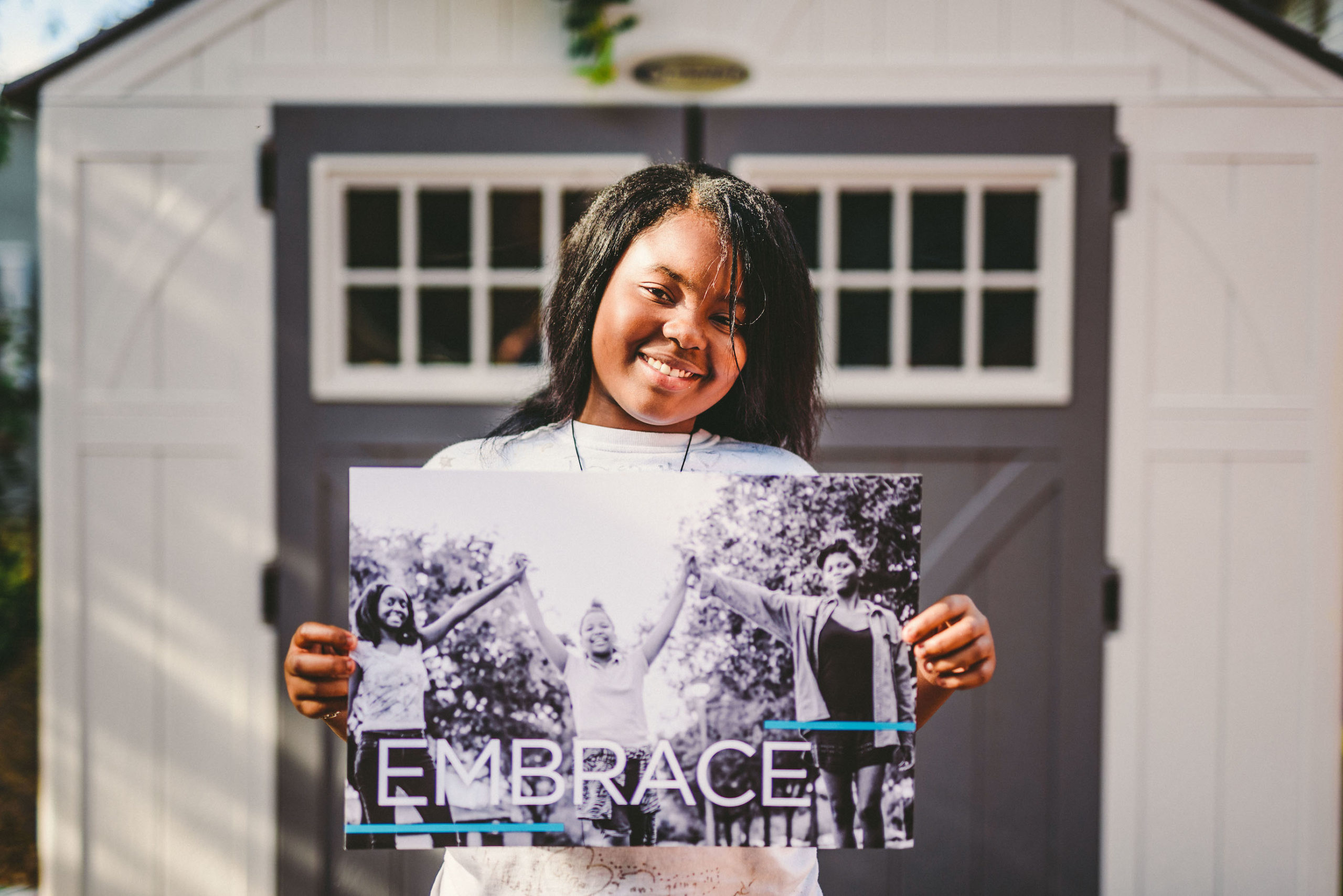 Handy Nonprofit African American holding a black and white poster that shows three people with the word Embrace
