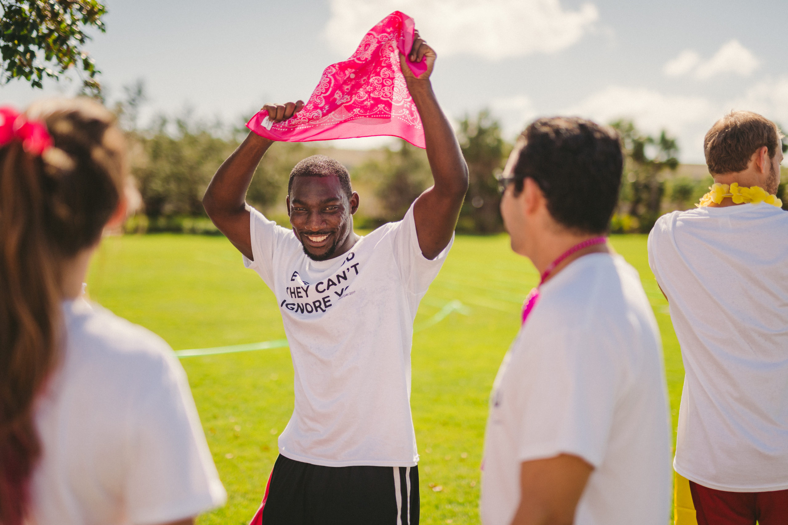 Marketing for nonprofits Handy Nonprofit African American man holding a pink bandana over his head surrounded by people