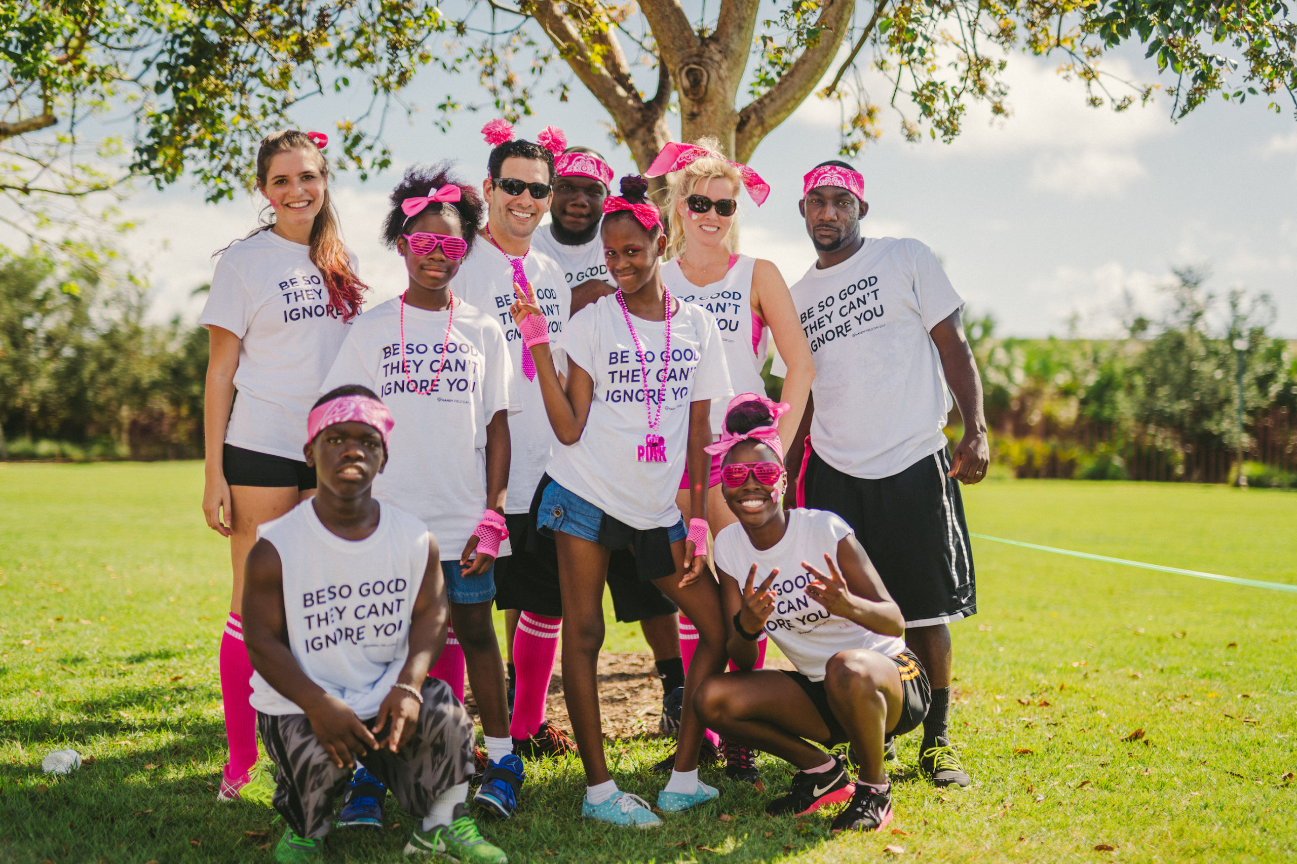 Marketing for nonprofits Handy Nonprofit Group of people with pink bandanas, necklaces and gloves posing for the camera in a field