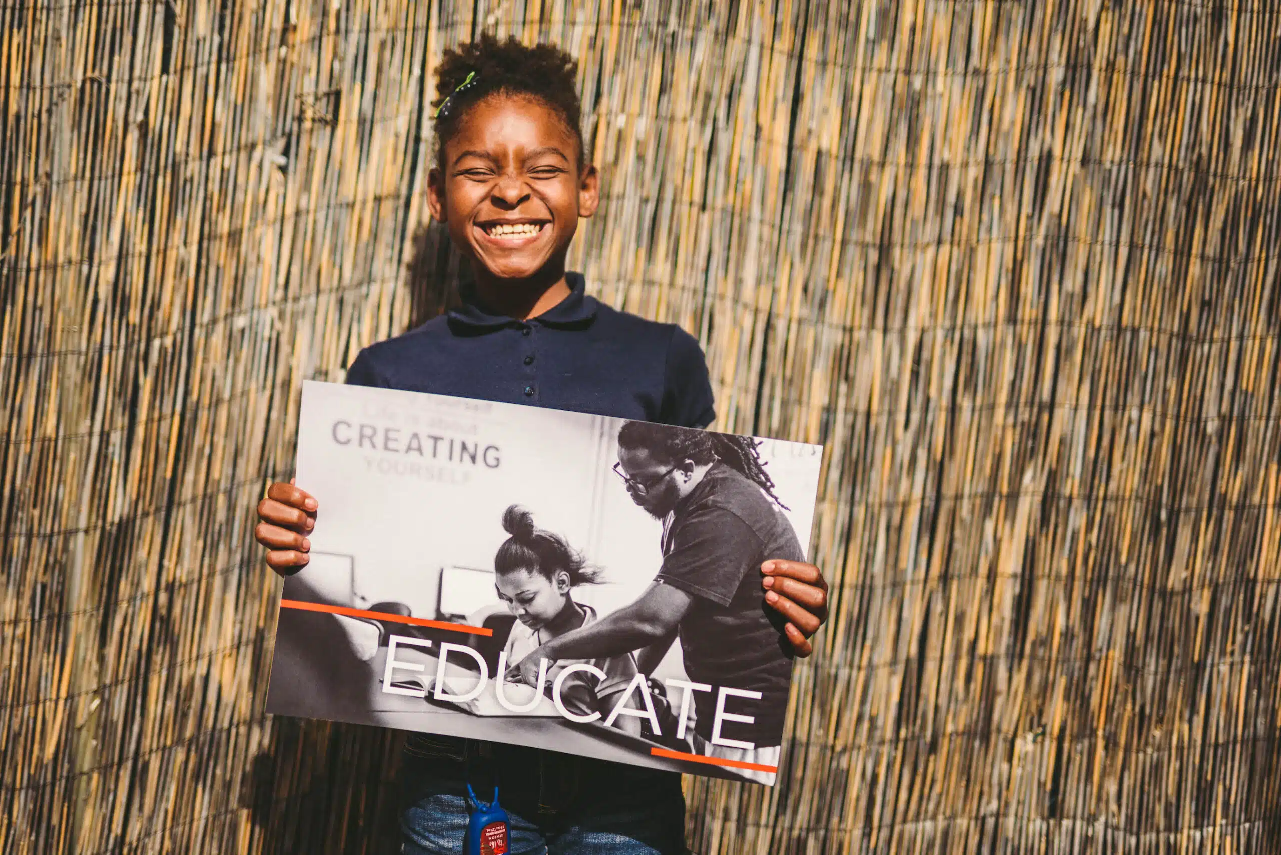 Handy 28 African American holding a black and white poster that shows two people with the word Educate