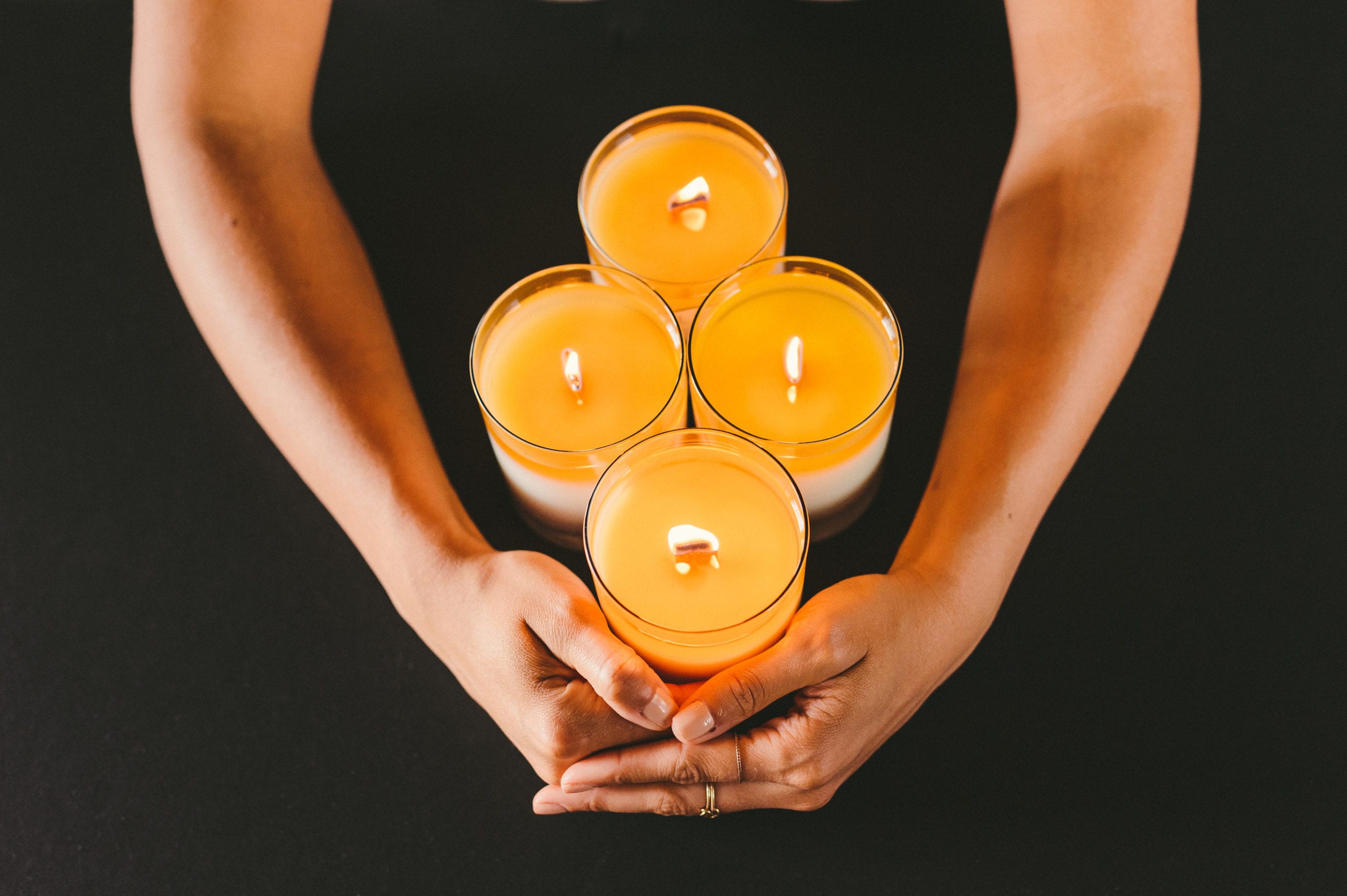 IKD Overhead view of woman's arms enclosing a group of four lit candles