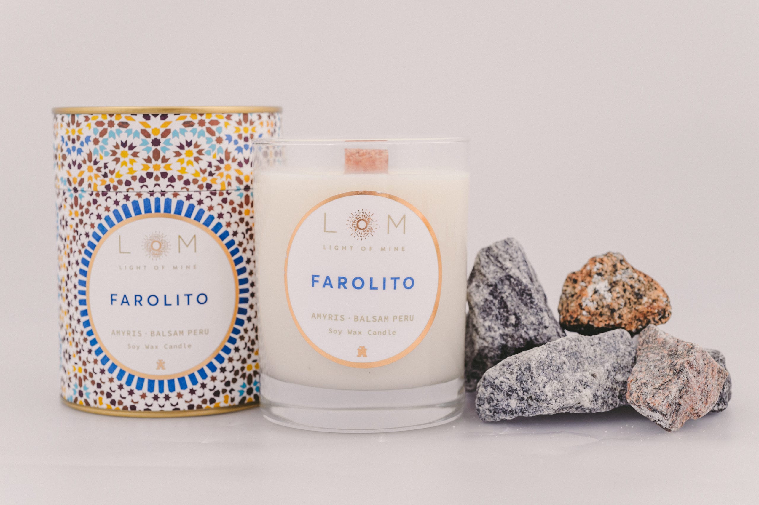 Two Light of Mine Farolito brand with Amyris and Balsam Peru soy wax scented candles next to a few stones