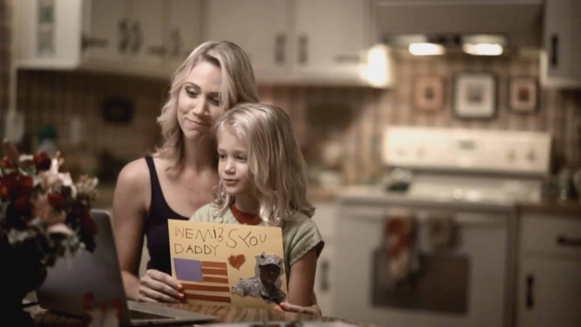 Mother with daughter on video chat with girl holding drawing for her dad