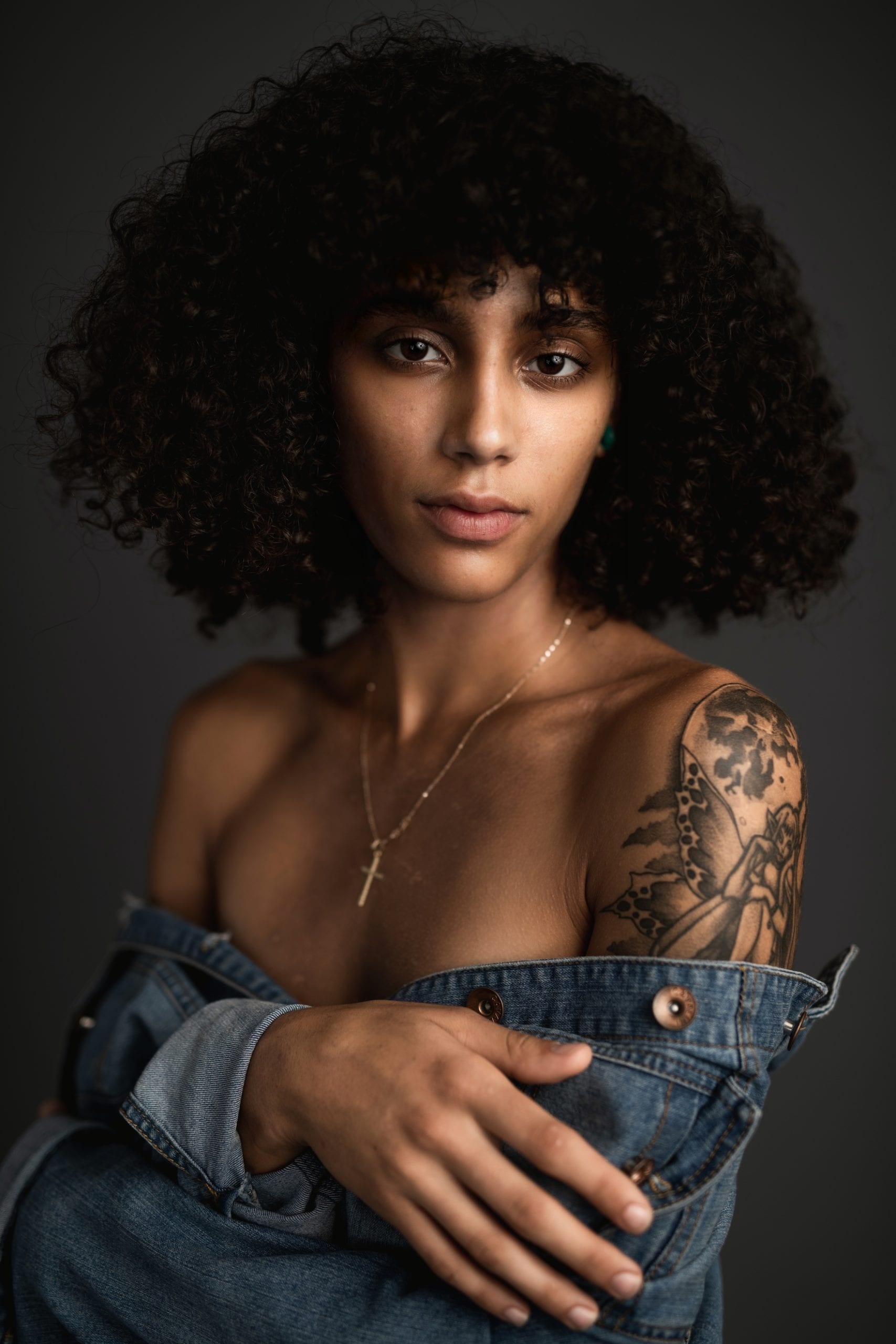 IU C&I Studios Post South Florida Model Jasmine Morales with black poofy hair looking into the camera with tattoo on her shoulder