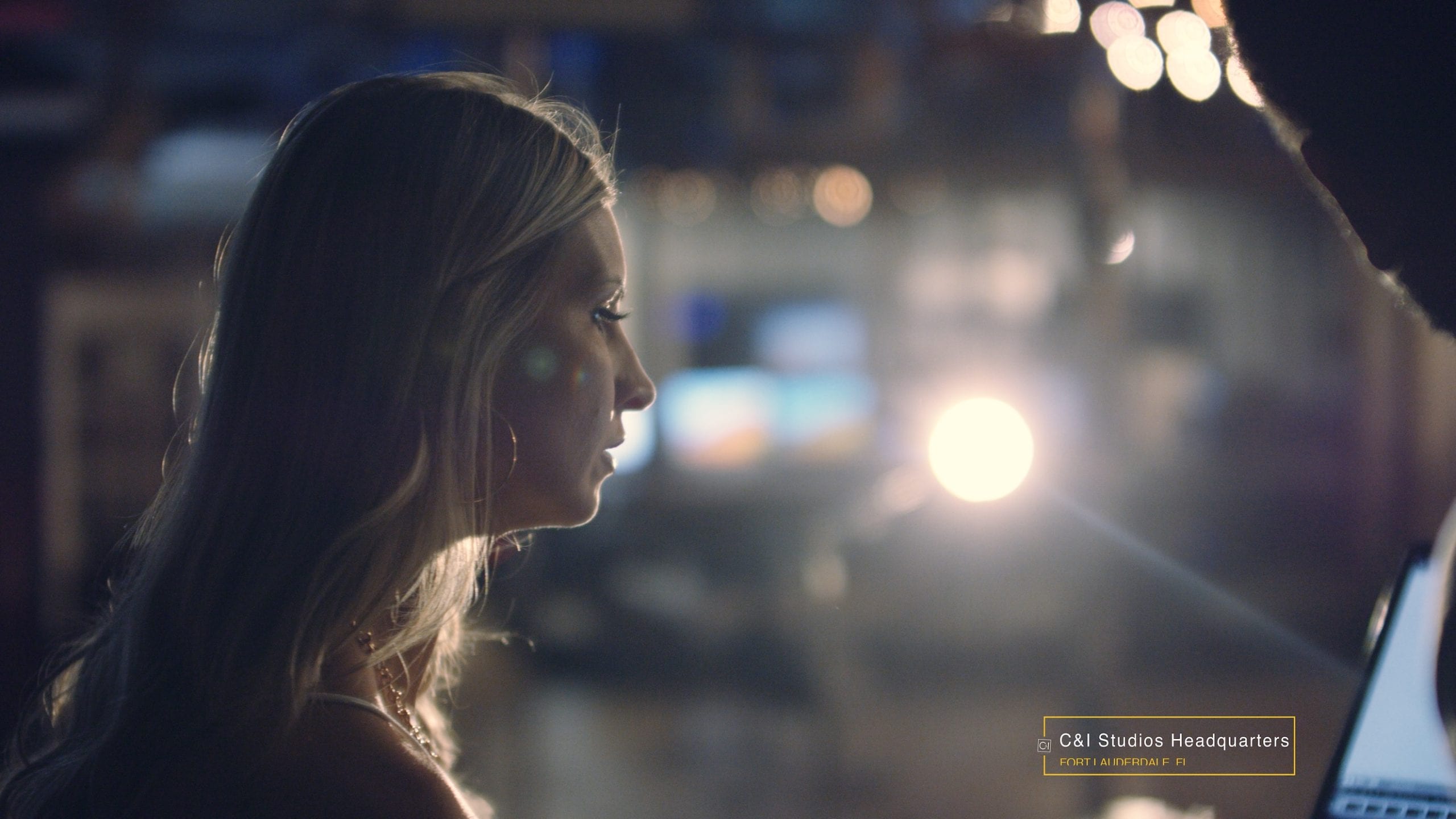 C&I Studios Company Culture takes you behind the scenes with side profile of a long, blond haired woman looking at a video display