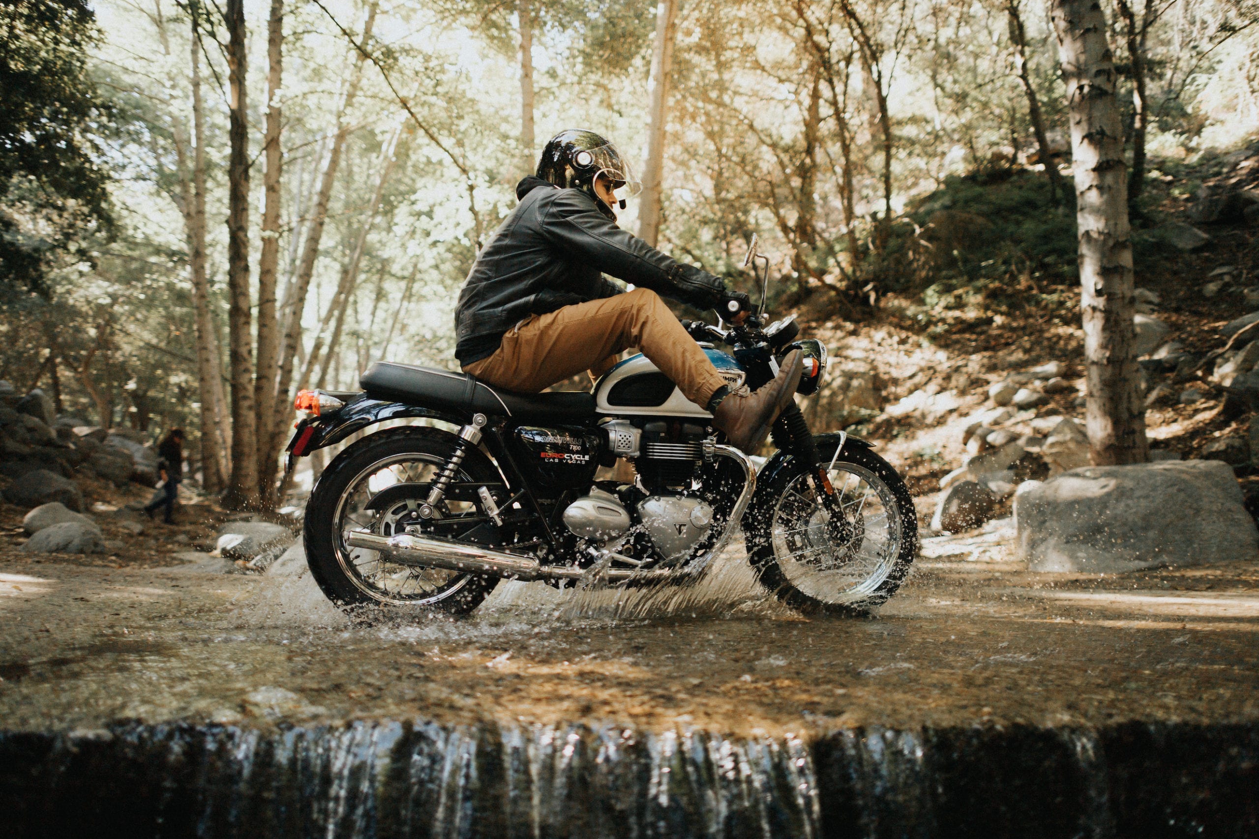 IU CI Studios Portfolio Triumph Motorcycles Euro Bike Photography Motorcycle rider riding through a shallow creek in Angeles National Forest with feet in the air