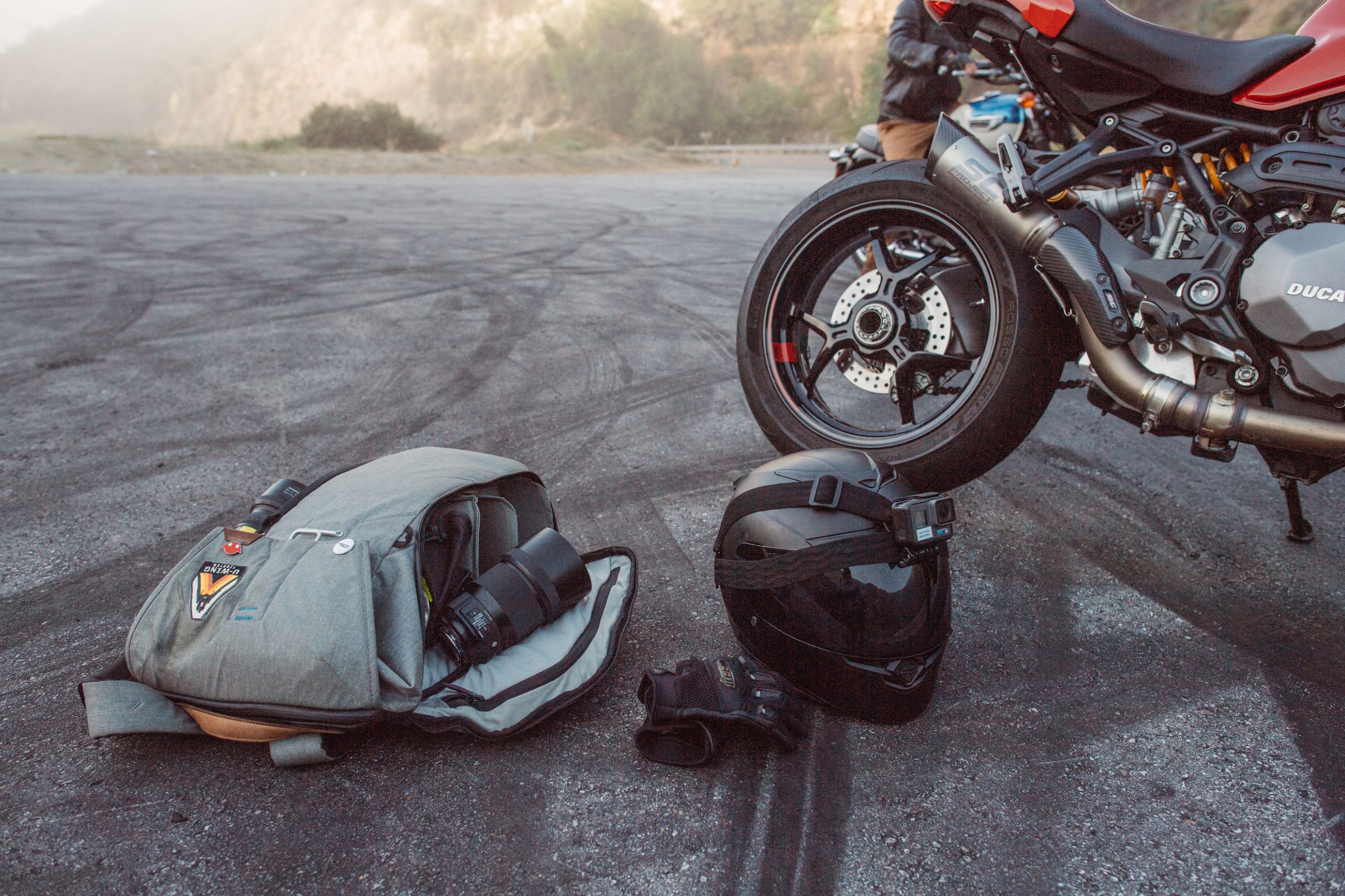 Behind the scenes on the set of the Triumph Motorcycles Euro Bike Shoot with view of the back side of the bike along with helmet with camera, backpack and leather gloves on the ground