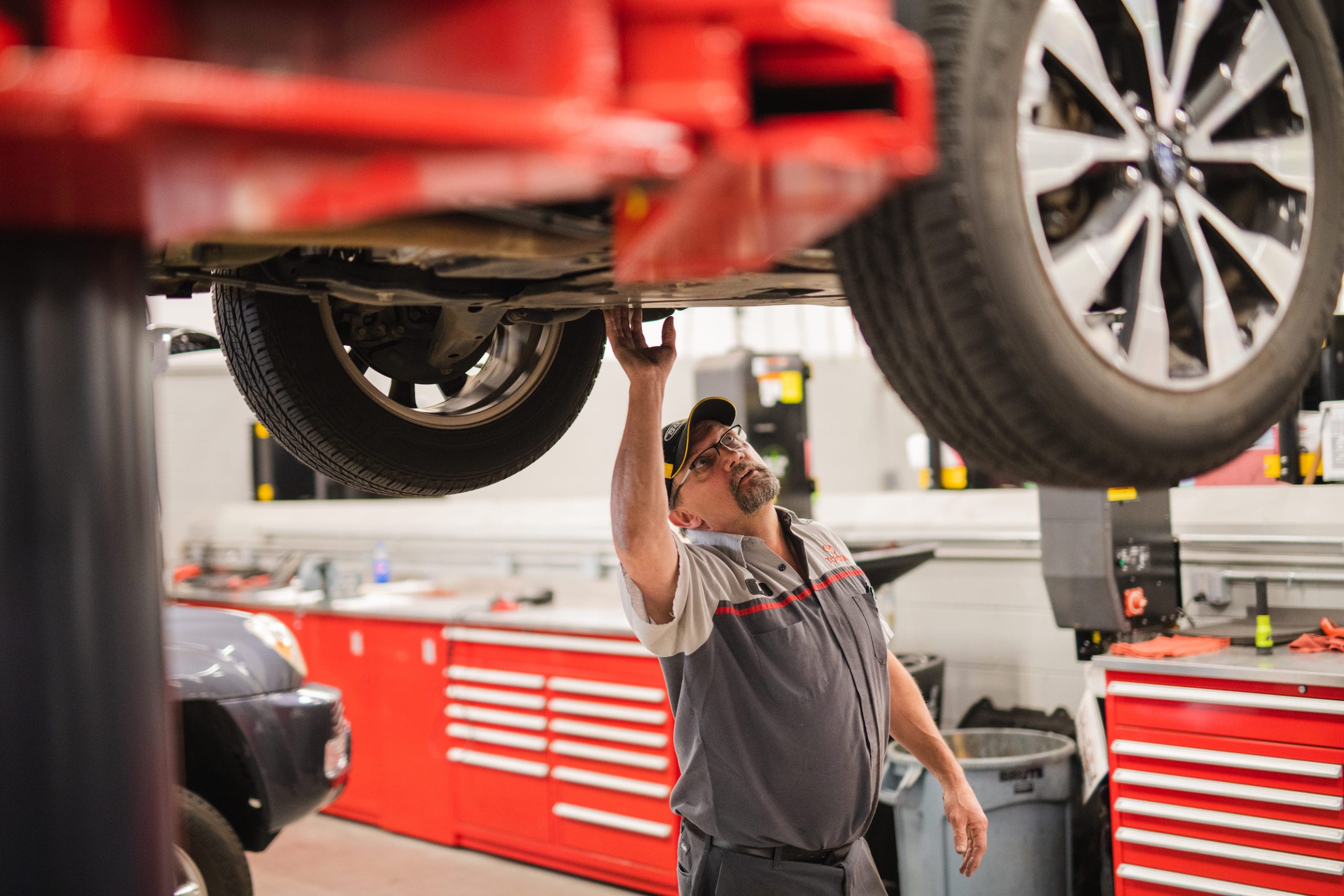 Mechanic looking at the underside of a car in a garage