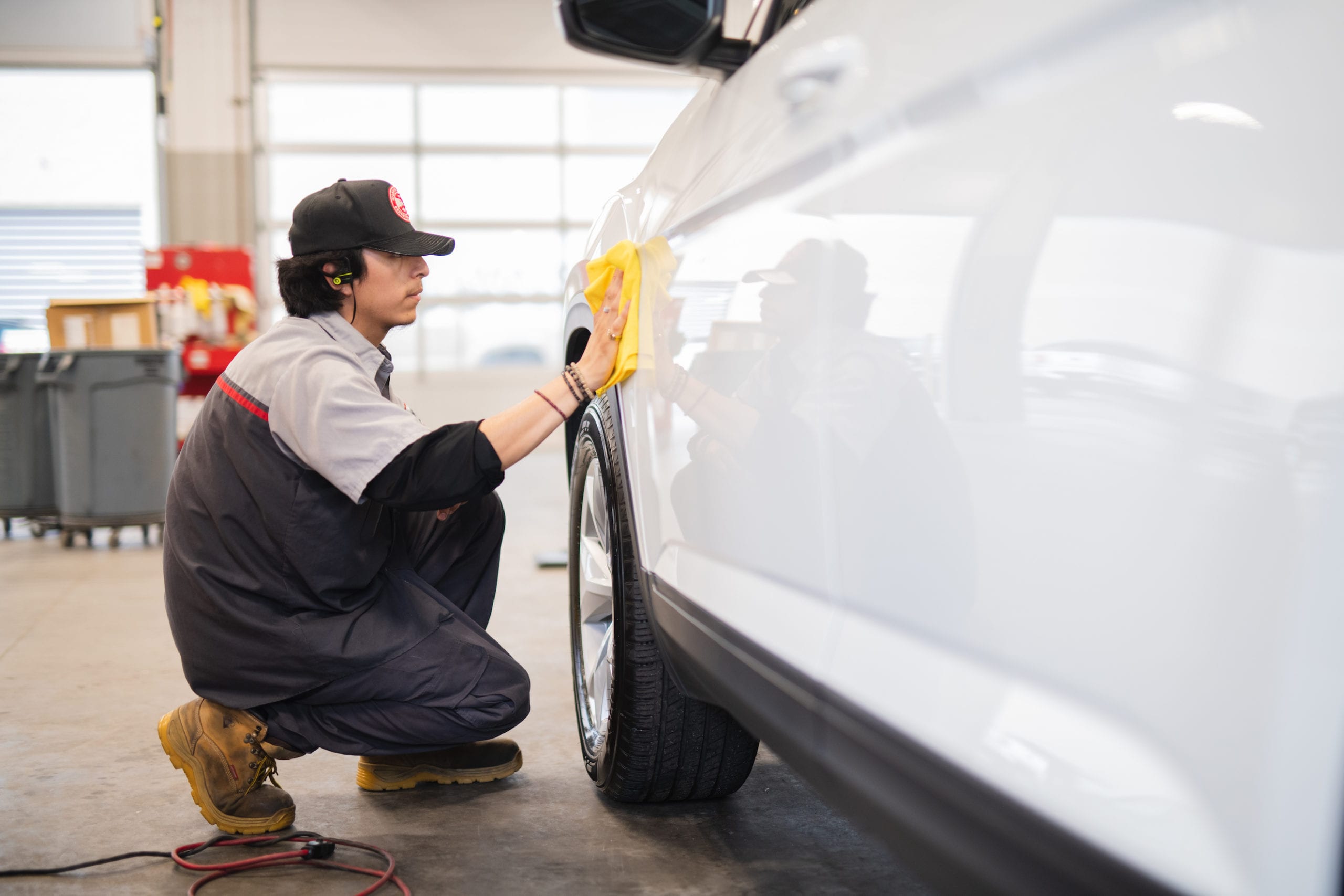 Man polishing the side of a white car with a yellow cloth