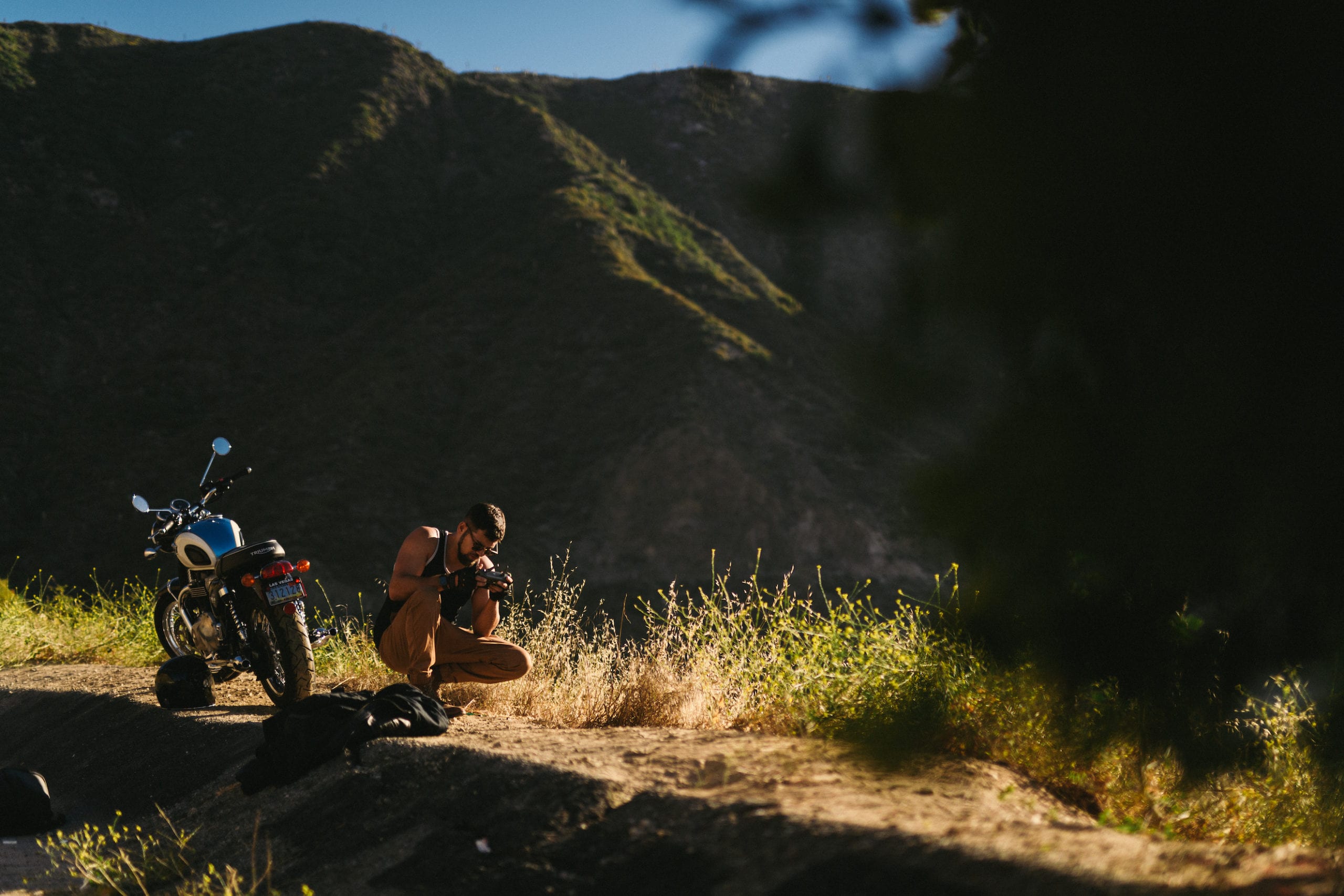 Cameraman taking picture of something on the ground near the motorcycle.