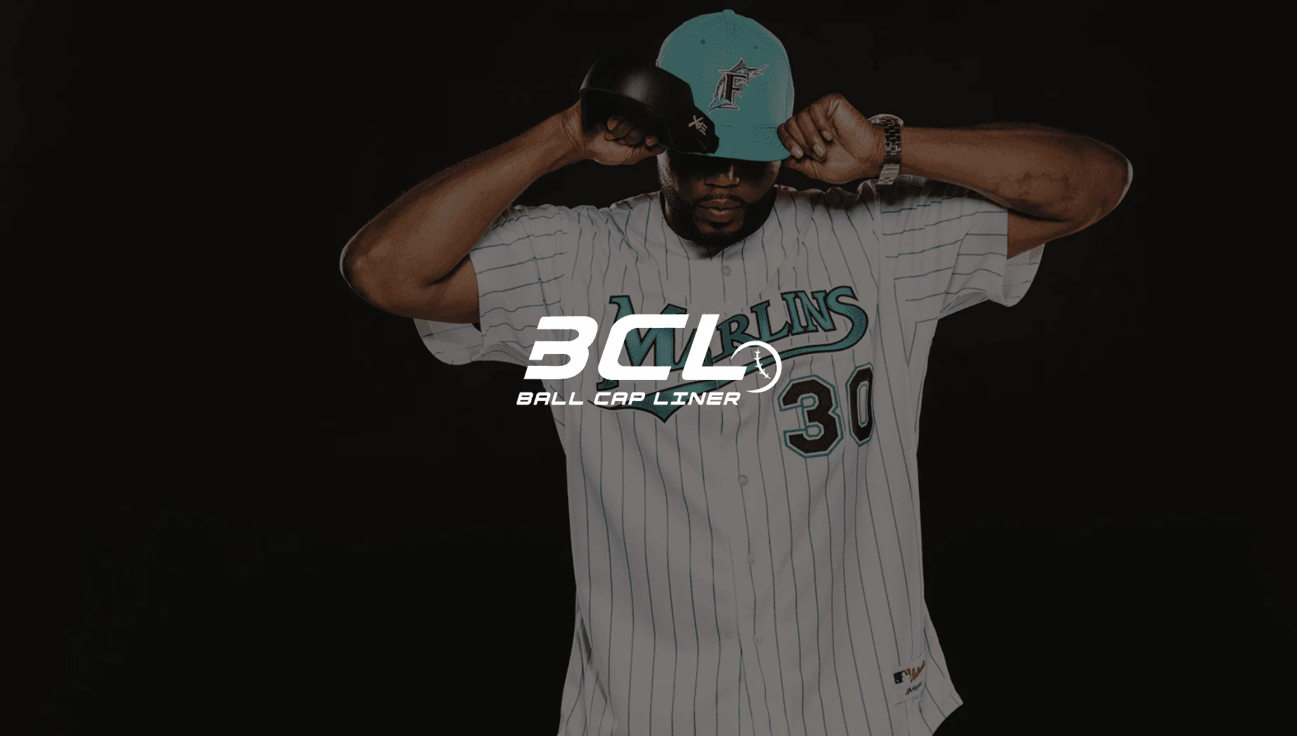 Keyword: Web Development .IU C&I Studios Page White BCL Ball Cap Liner logo against an African American man wearing a Marlins jersey and cap posing for the camera looking down adjusting his cap