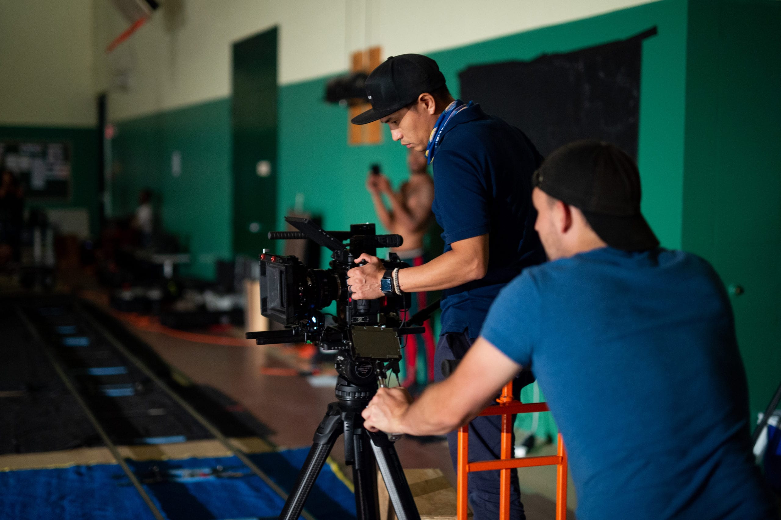 Nike Two male film crew members adjusting equipment for filming on a basketball court