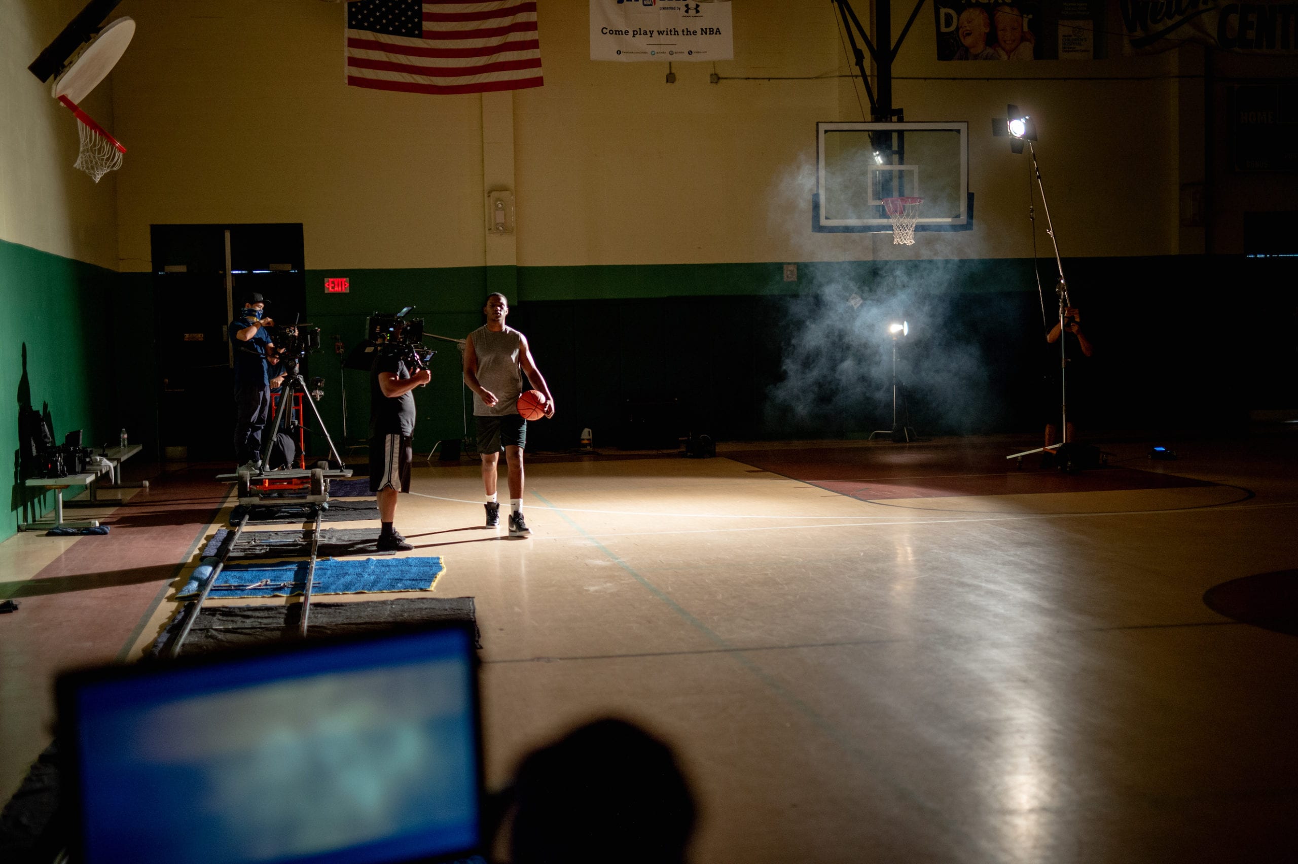 Nike scene being filmed on a basketball court in a gym with a basketball player holding a ball walking on the court surrounded by a film crew
