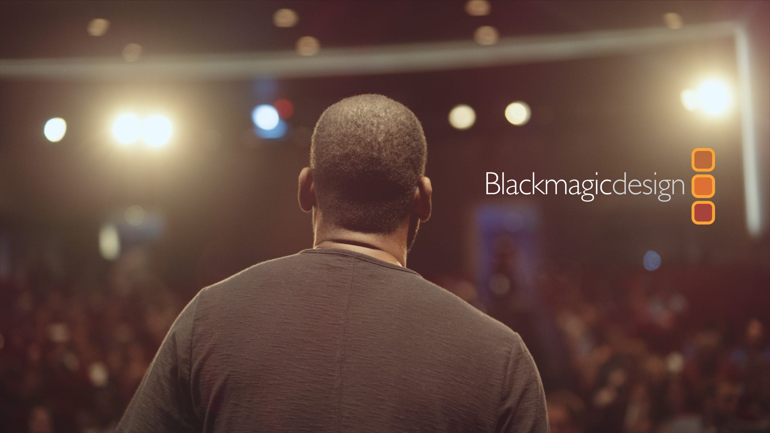 Editfest 2019 sponsored by Blackmagic Design logo with view from behind of a man addressing an audience in the background