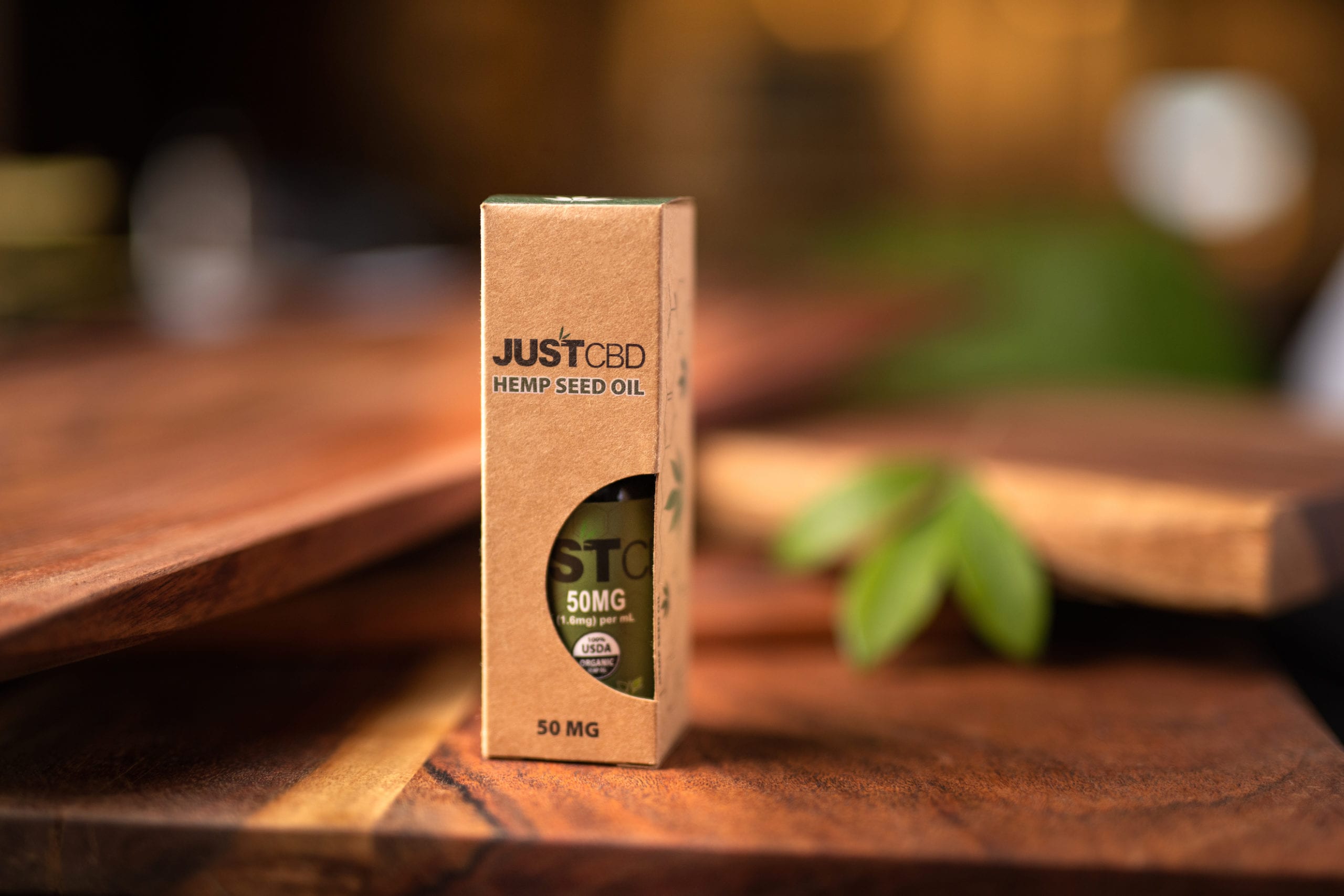JustCBD Product Photography and JustCBD Products JustCBD Hemp Seed Oil container on display on a wooden table