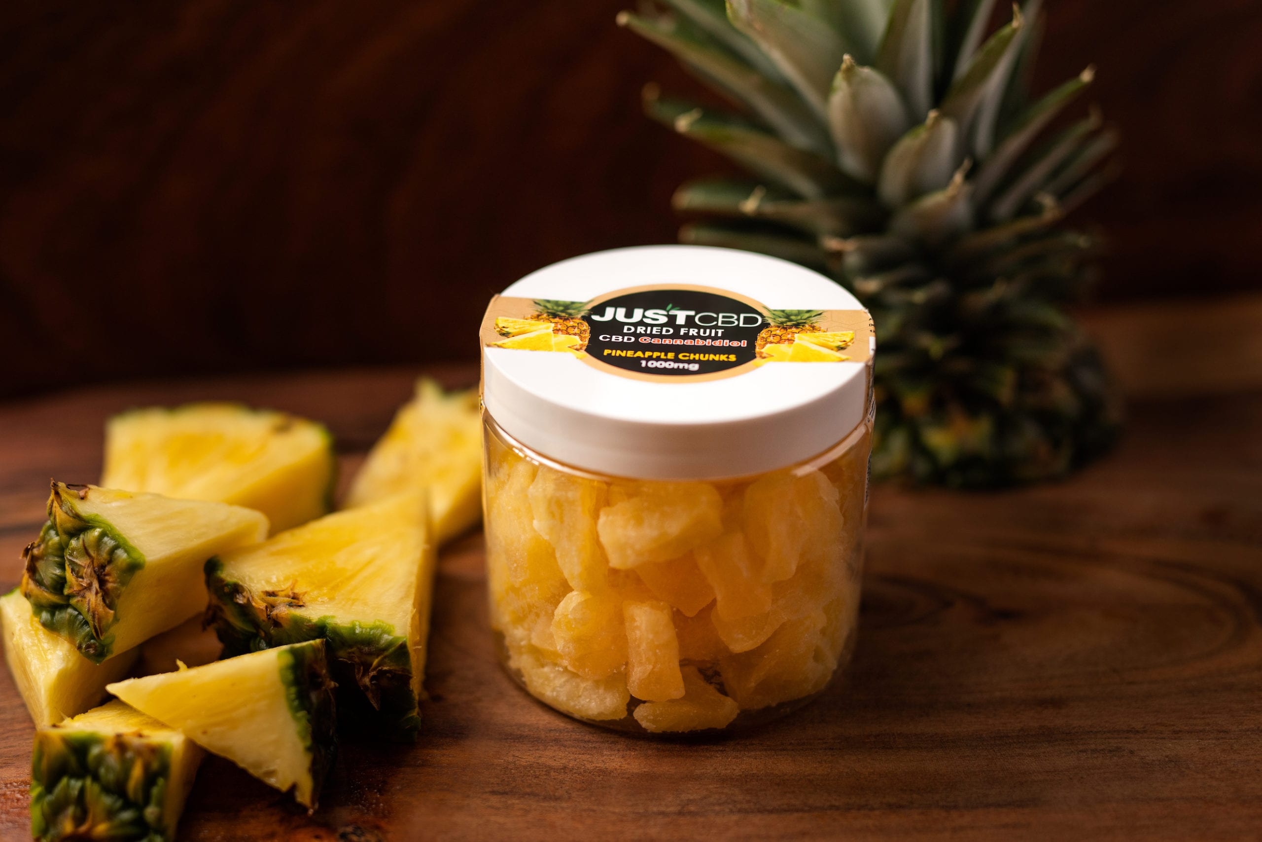 JustCBD Product Photography and Just CBD Products Container of dried fruit pineapple chunks on display with real pineapple chunks nearby
