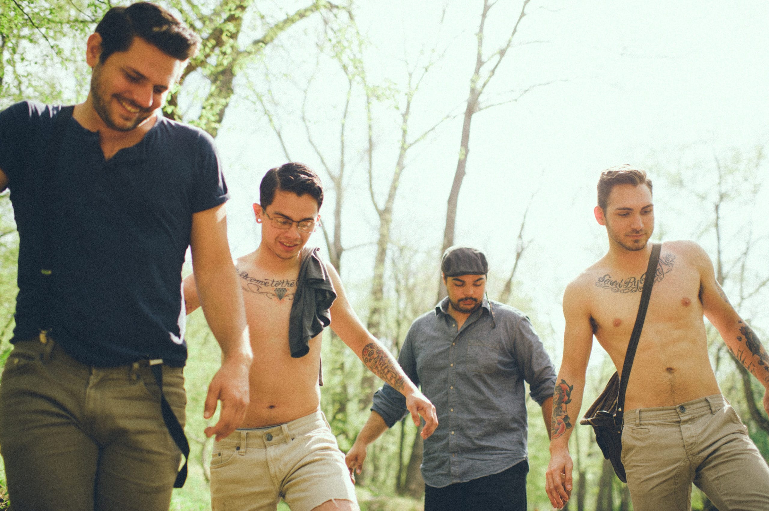 Kids American Indie Rock Band. Four men-two without shirts and have tattoos on arms and chest.