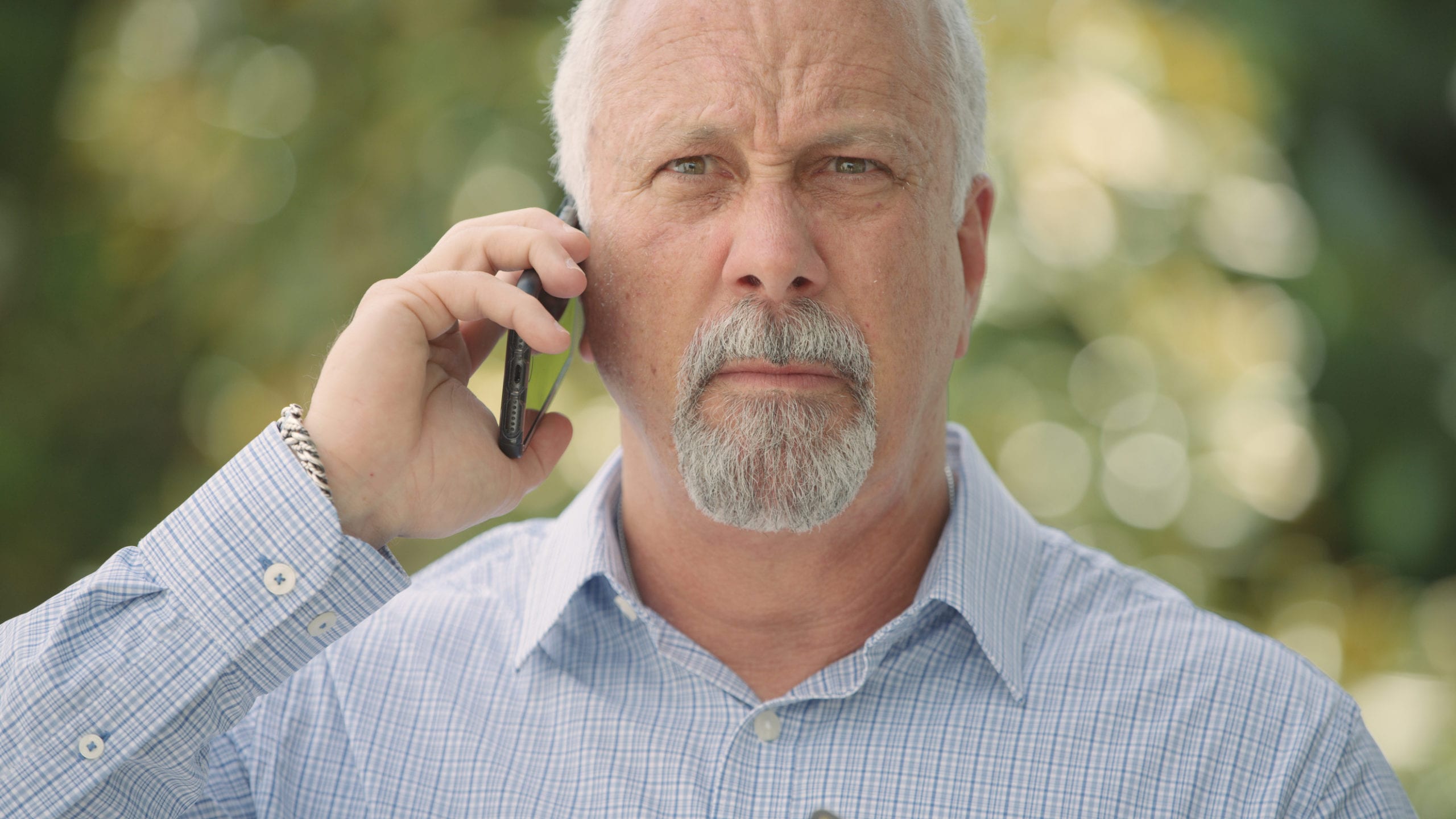 Doctor wearing light blue grid shirt talking on cell phone