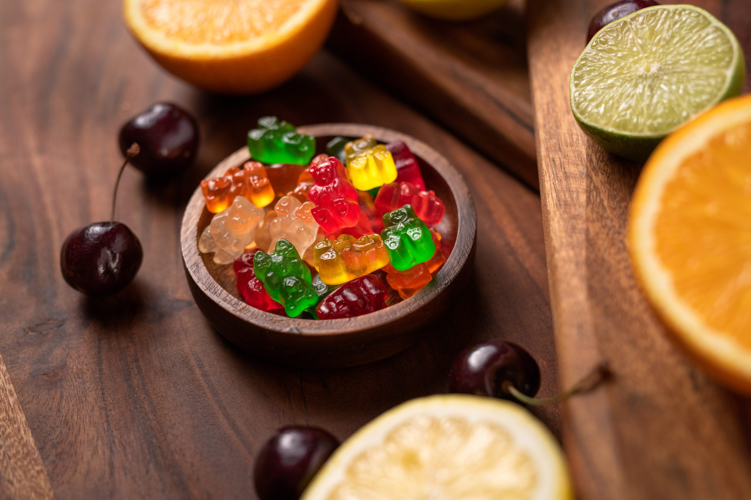 Gummy bears on display surrounded by cherries and slices of citrus fruit