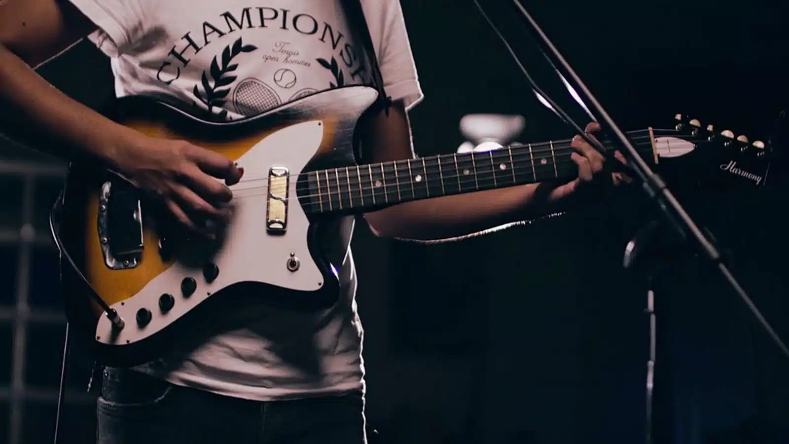 Closeup of man playing a brown and white guitar