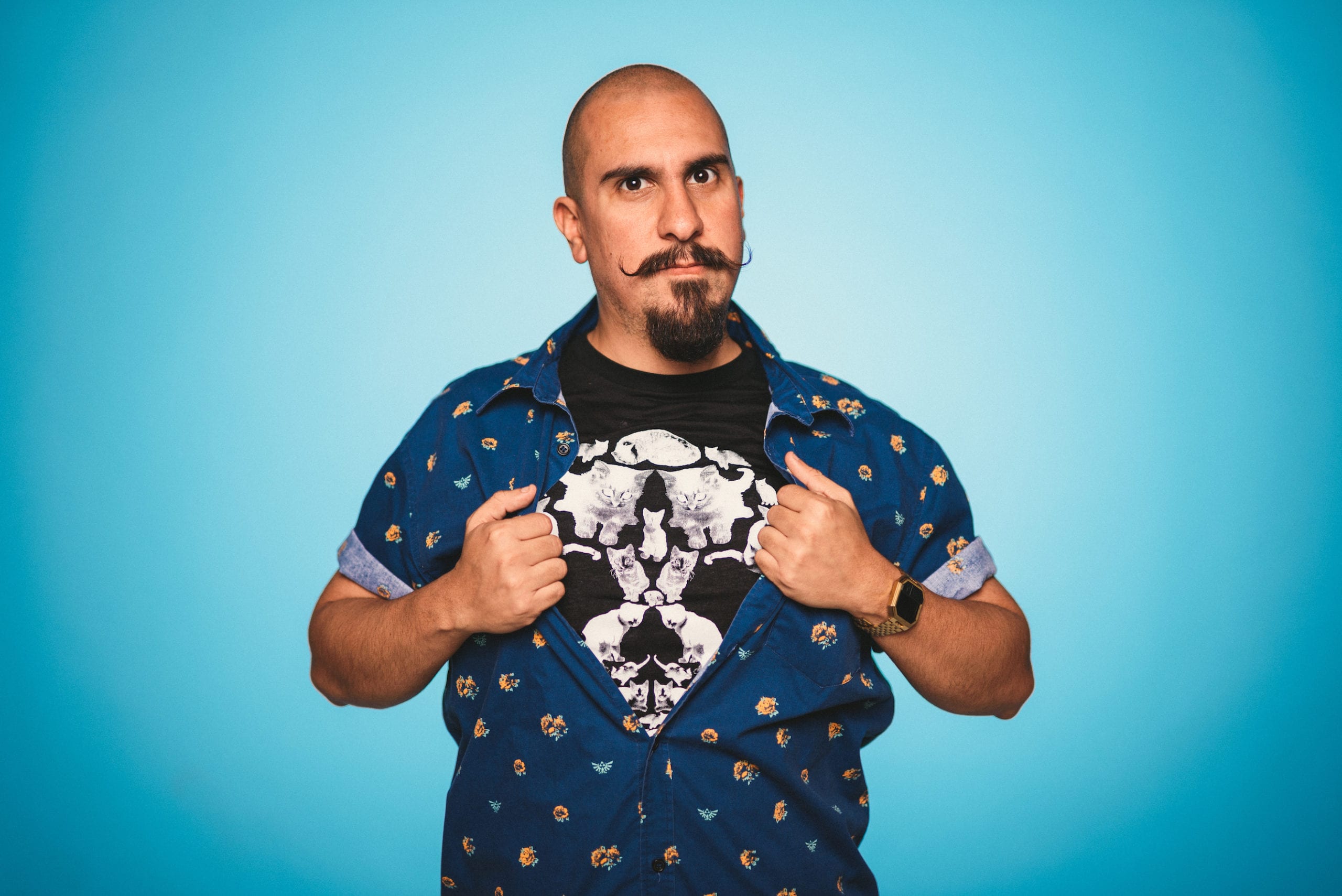 Bald man with a moustache posing for the camera with a light blue background