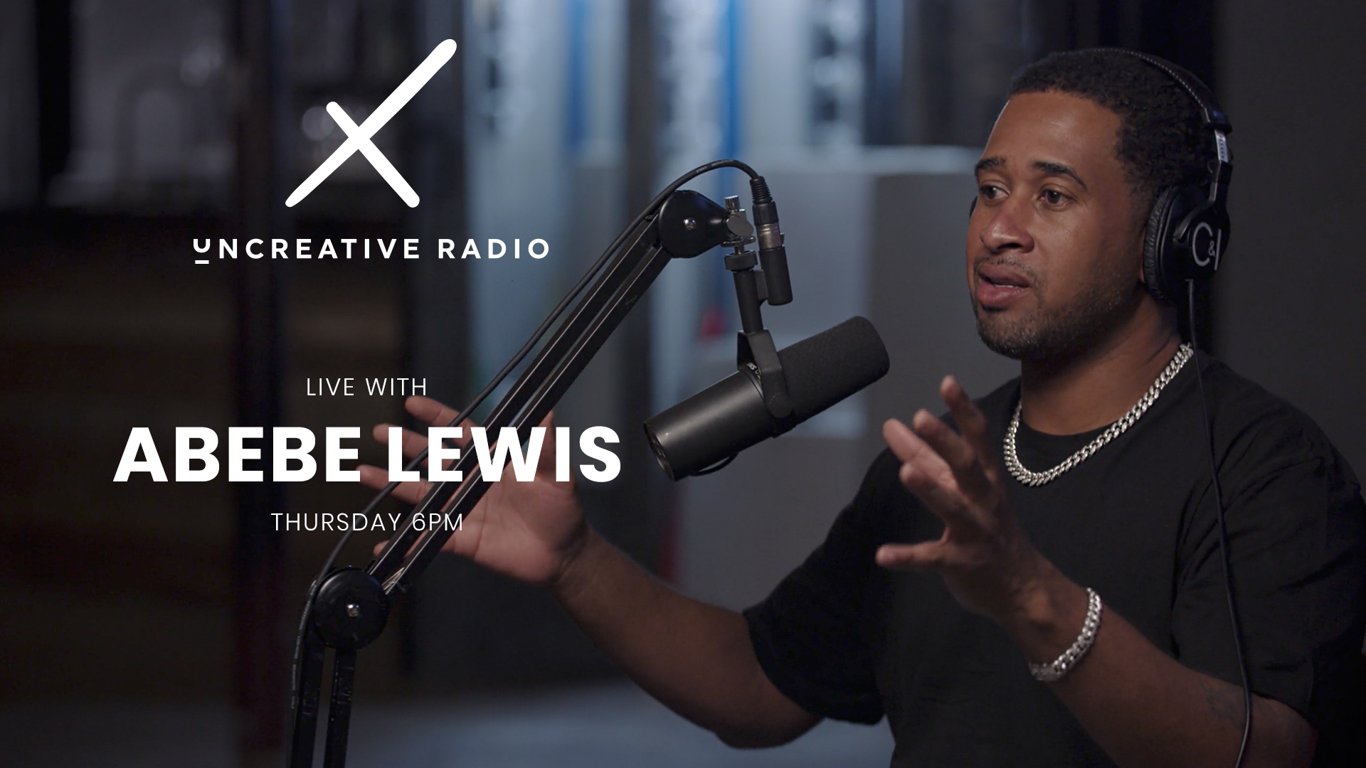 Uncreative Radio Live with Abebe Lewis title wearing black headphones by microphone gesturing with arms and hands in the air