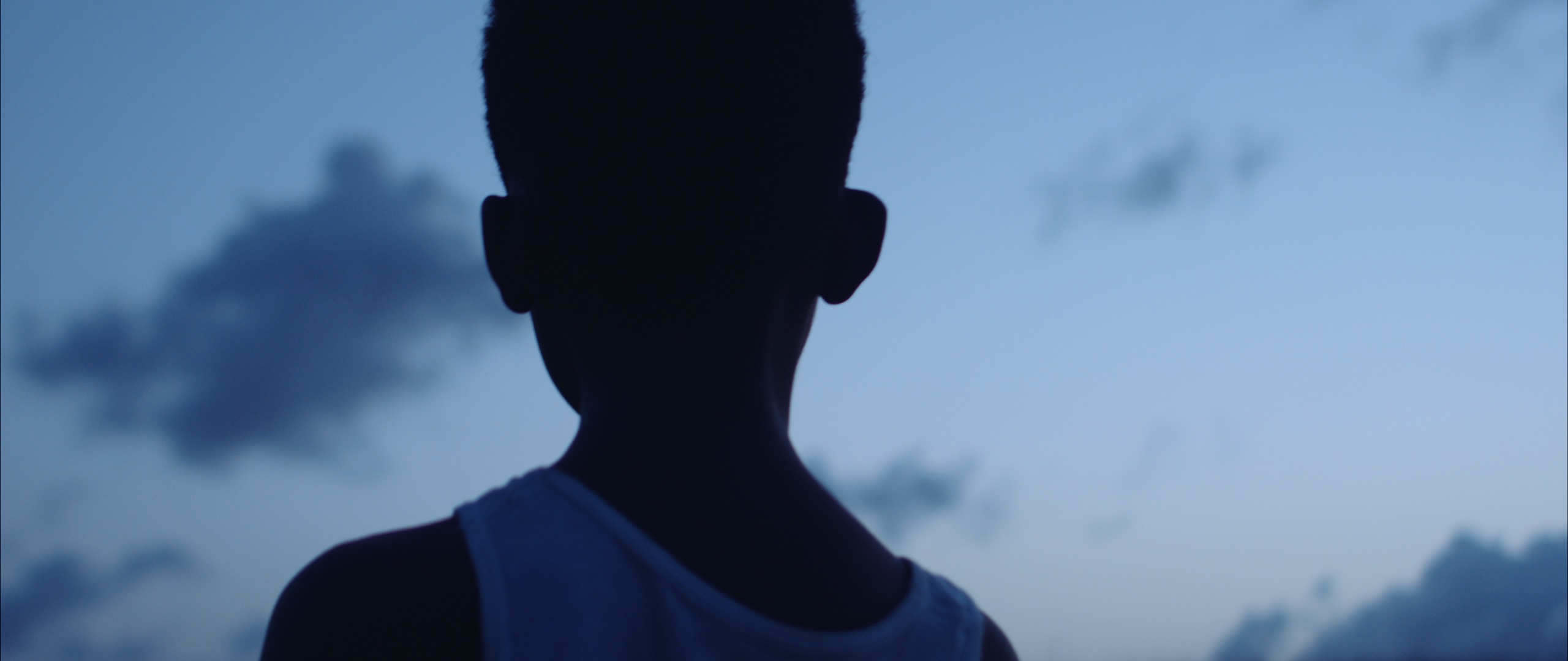 Black Violin Impossible is Possible Music Video with closeup view of a boy wearing tank to looking in the distance at dusk