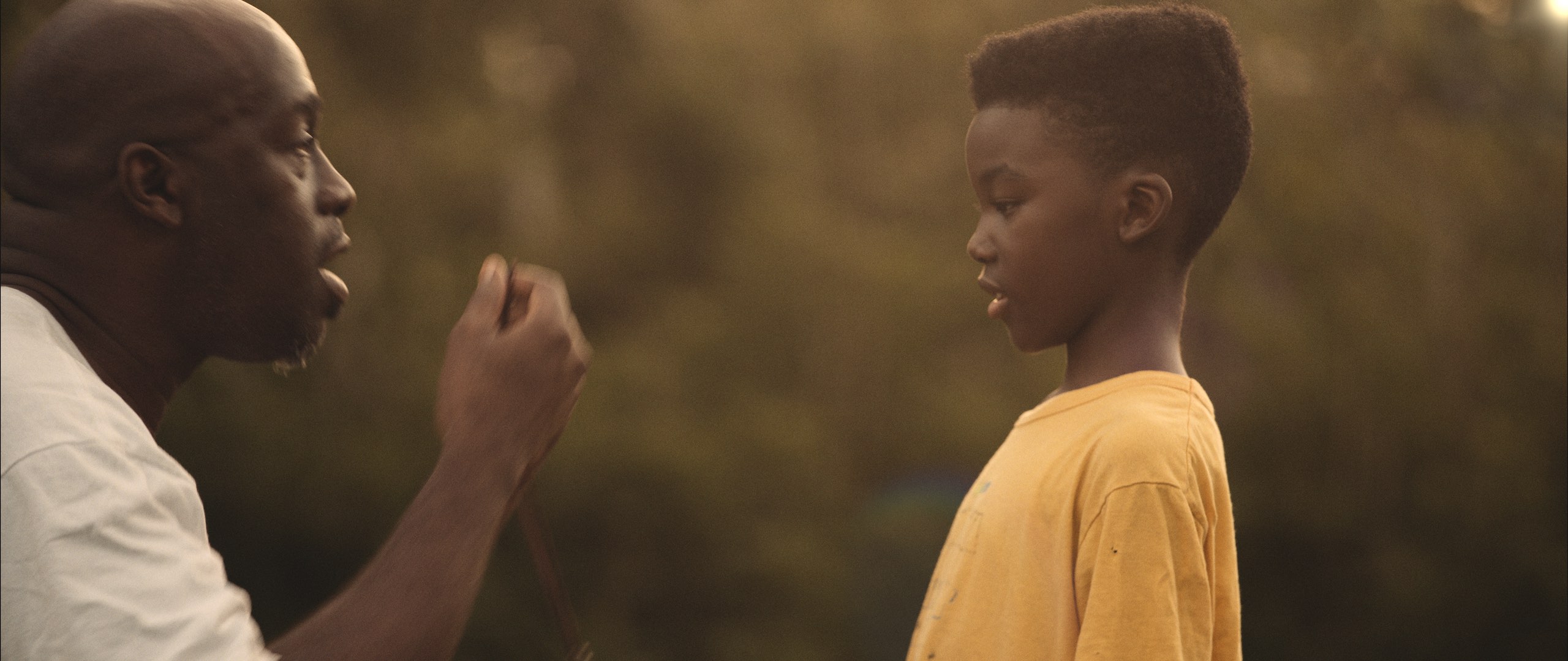 Black Violin Impossible is Possible Music Video with side profile of African American man talking with an African American boy wearing a yellow t shirt