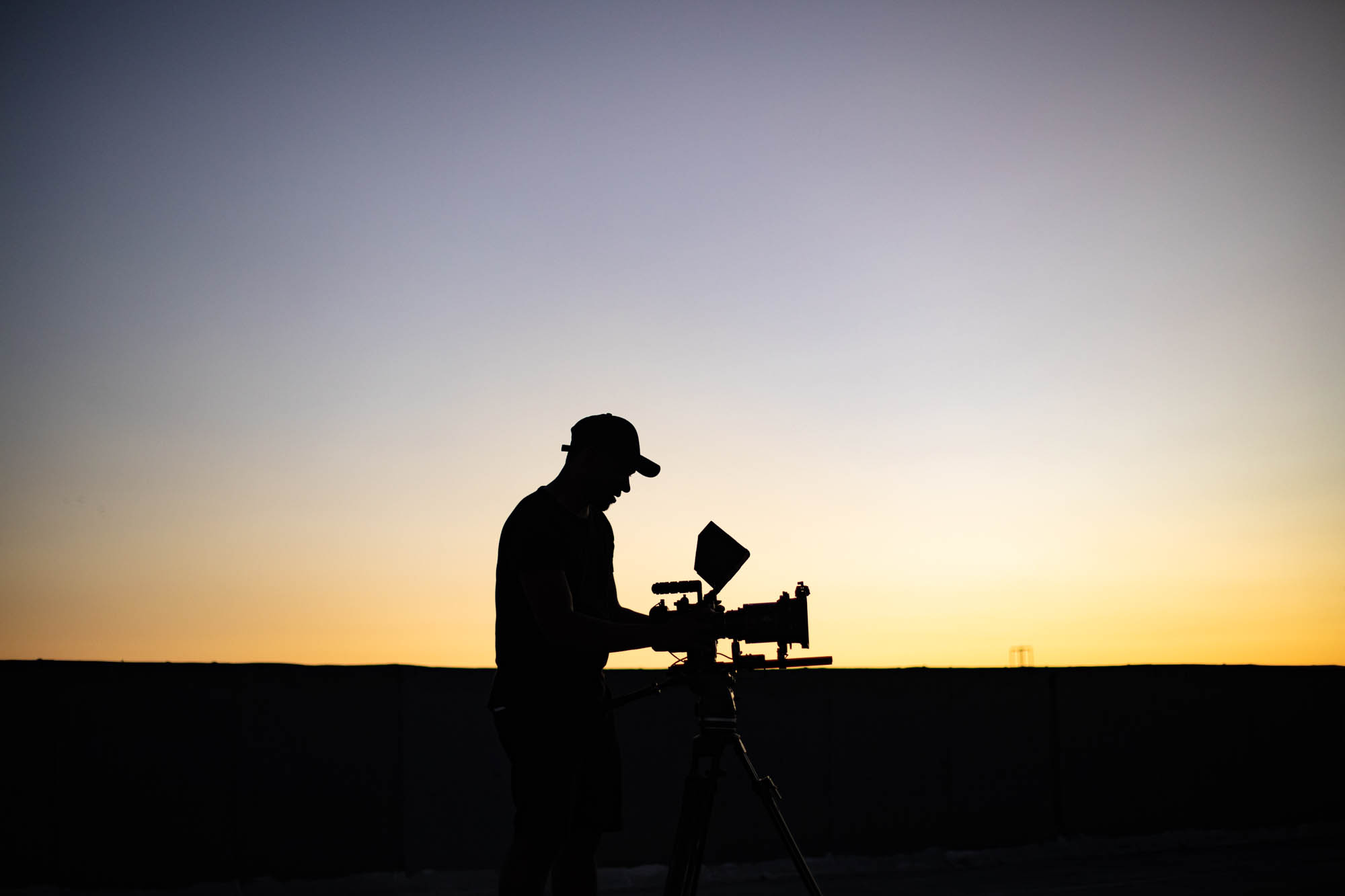IU C&I Studios Portfolio Black Violin BTS Side view showing silhouette of man using camera at dusk