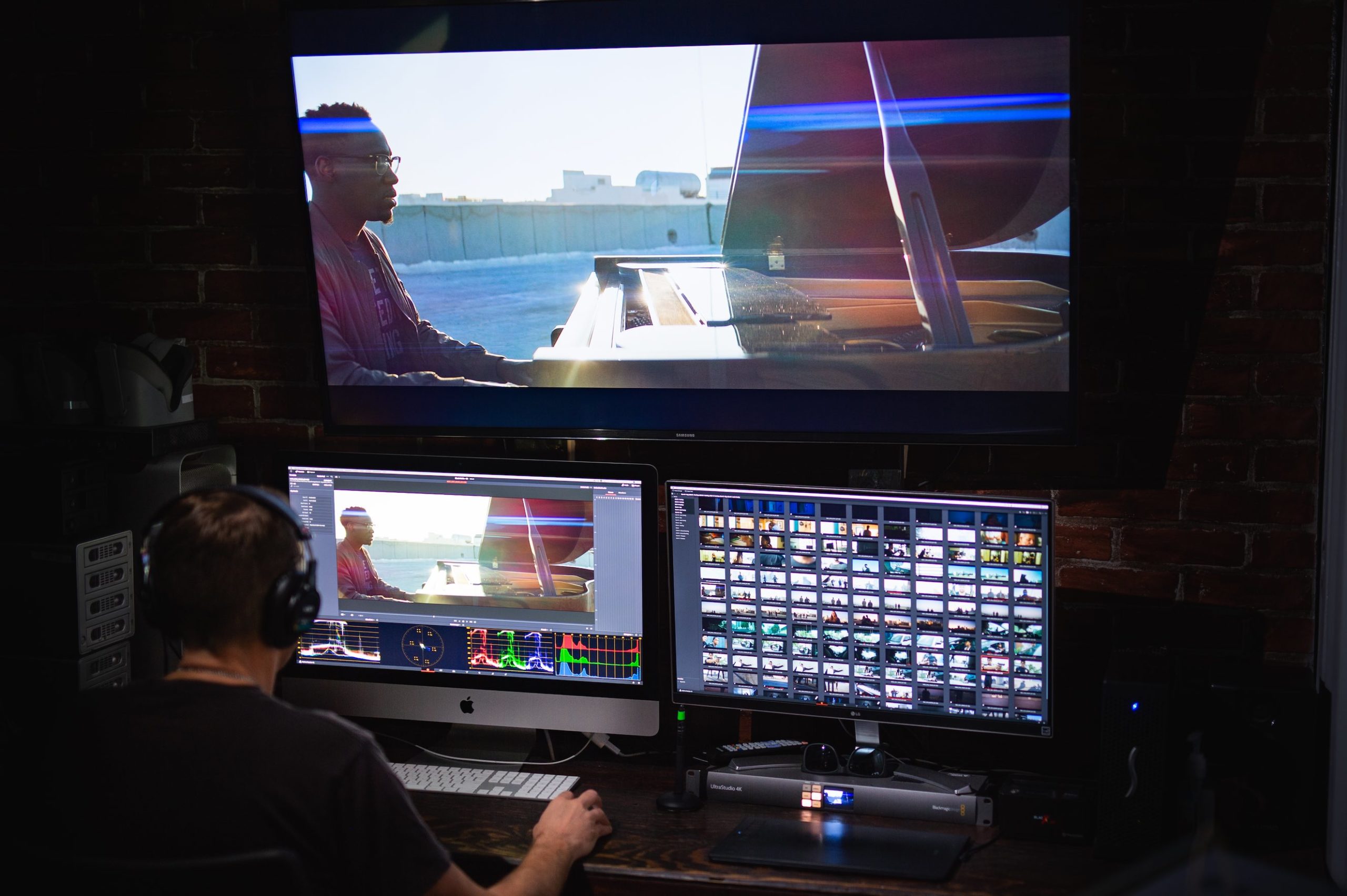 View from behind of someone wearing headphones working with audio and video software on a desktop