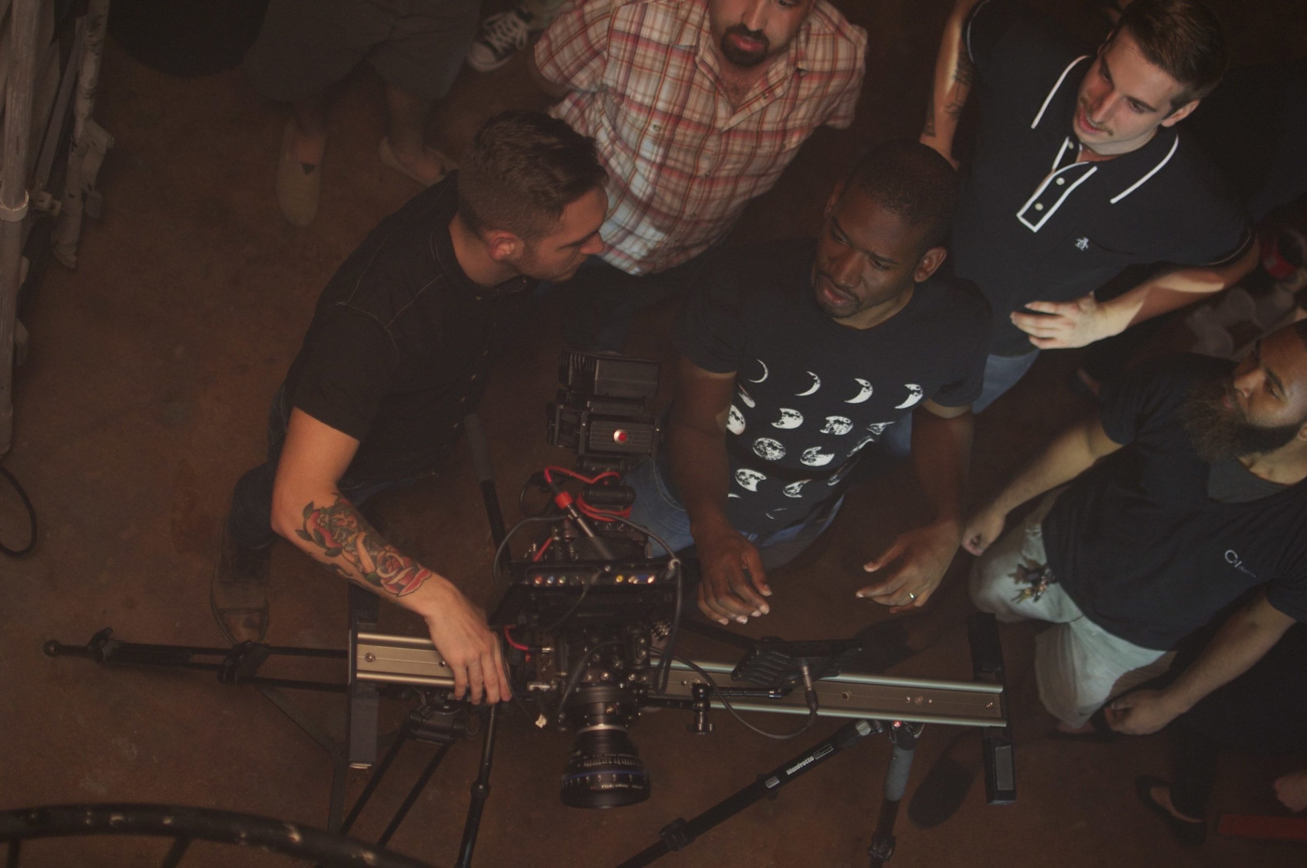 View from above of video camera and five men talking to each other
