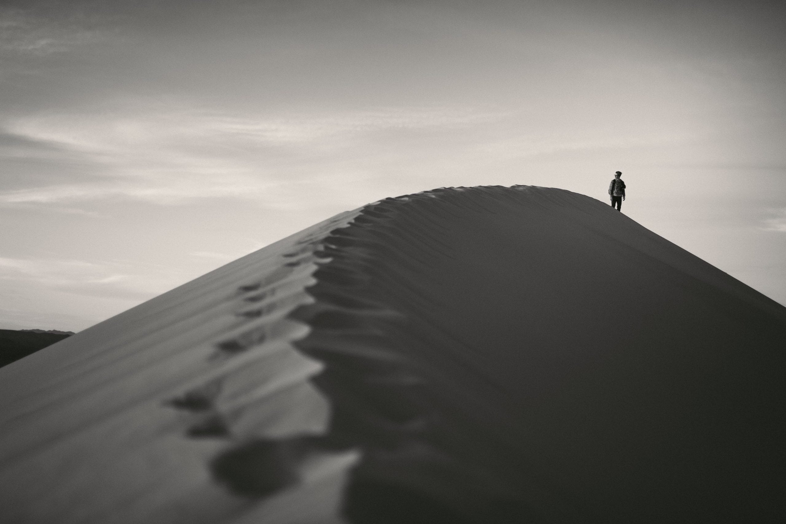 Professional Photography Services by C&I Studios Black and white of a man standing on a large sand mound in a desert