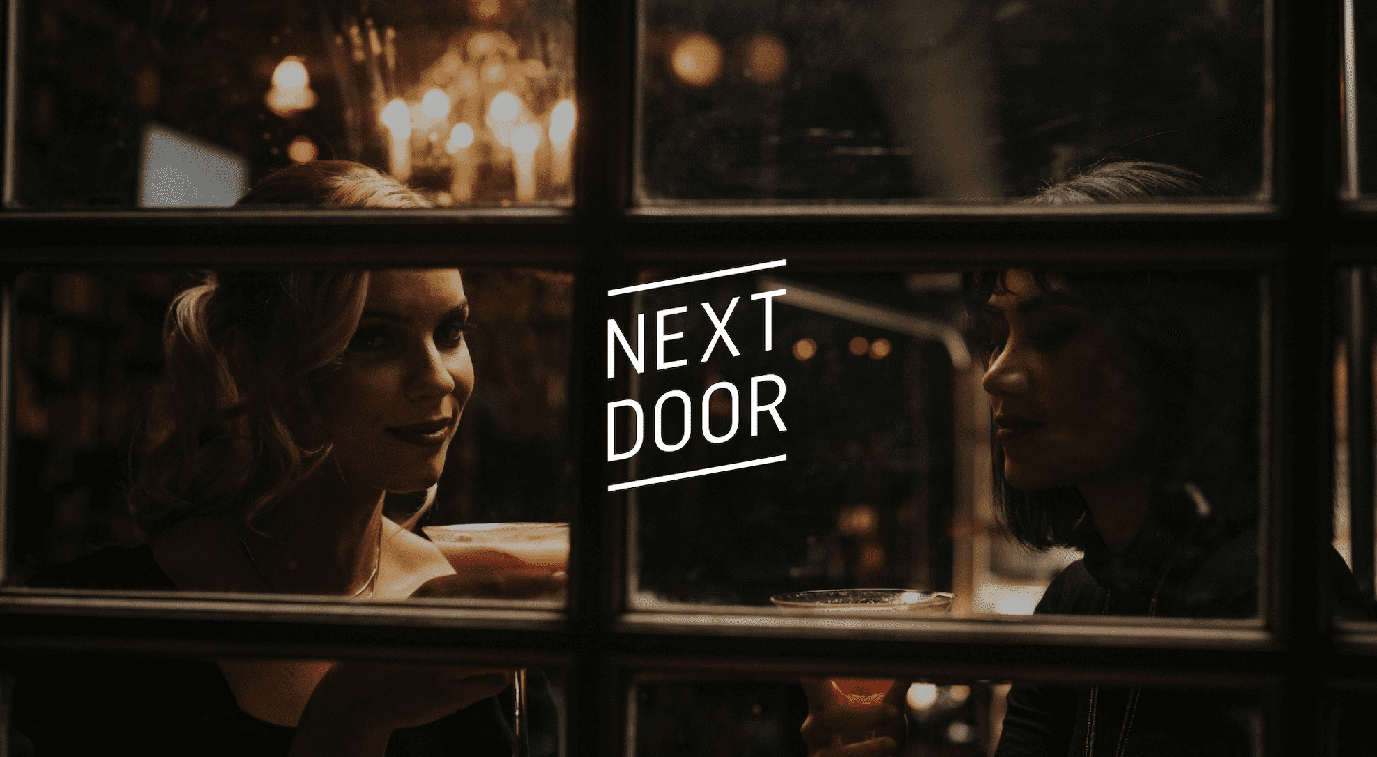 Next Door Rebranding Photoshoot White Next Door logo with a background showing two women looking out of a window while enjoying cocktails