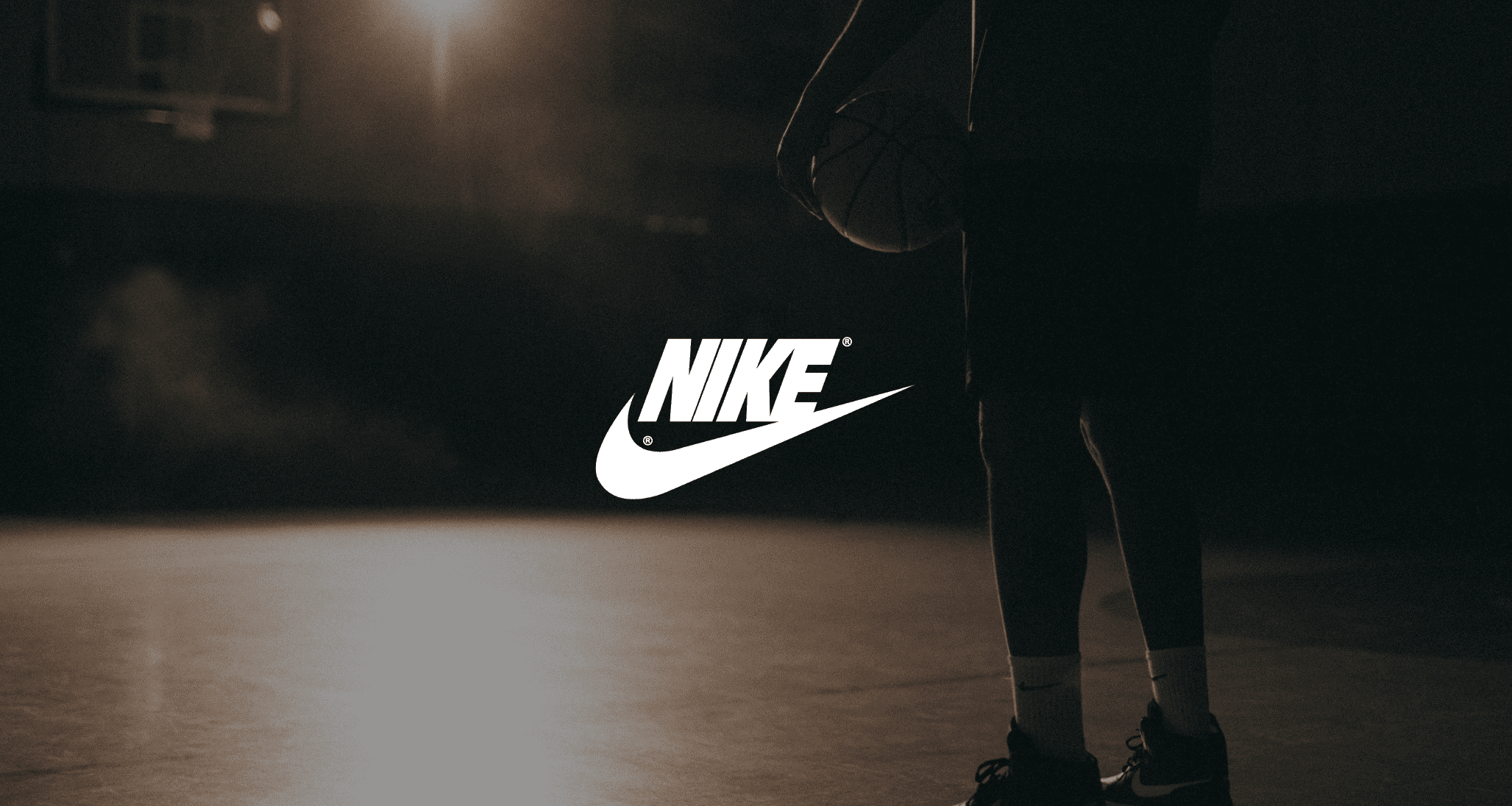 Video Production Services by C&I Studios White Nike logo against a dim view from behind background of a man holding a basketball on a basketball court
