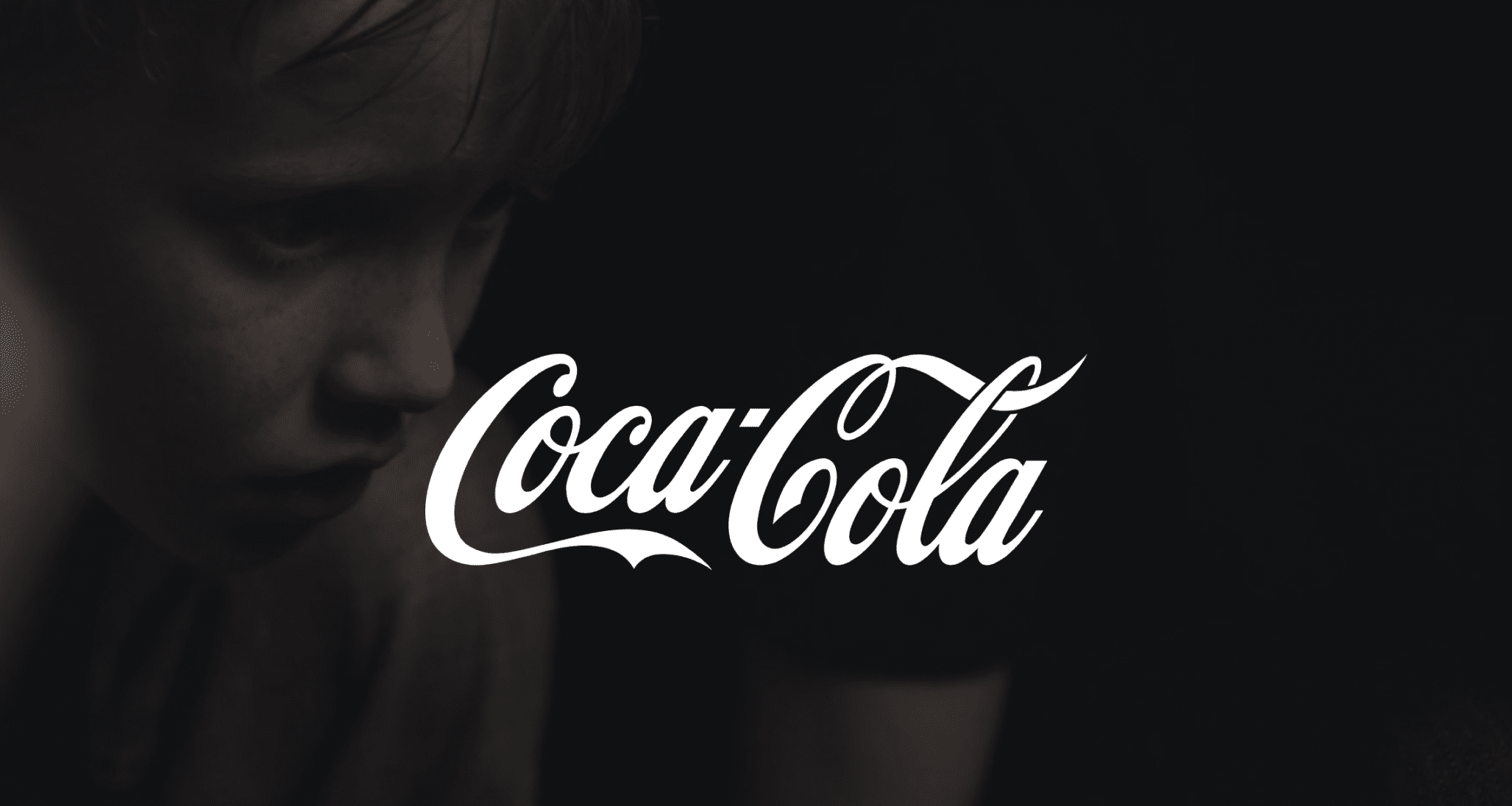 Professional Video Production Services by C&I Studios White Coca Cola logo against a dim background of a boy with freckles