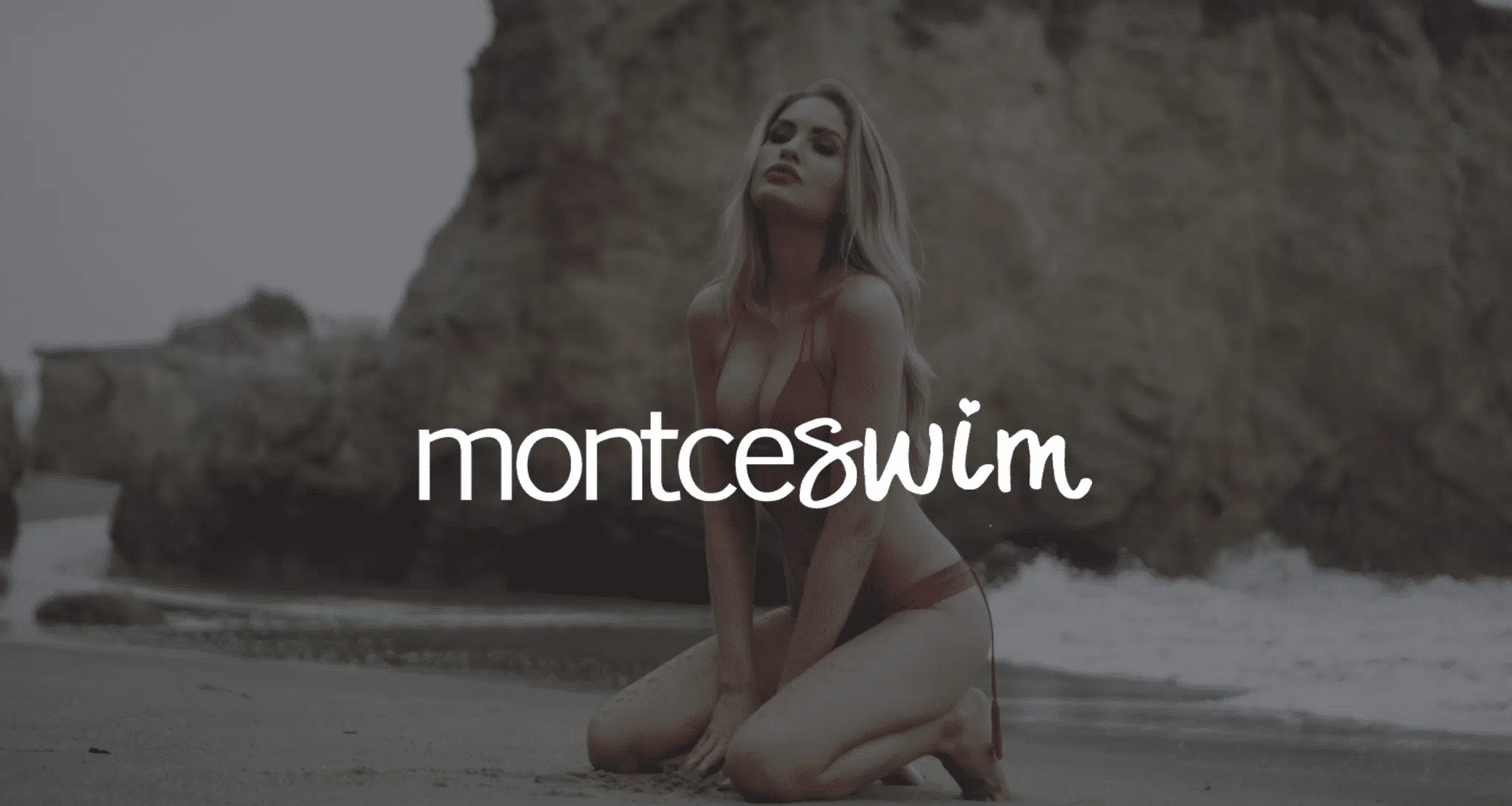 White MontceSwim logo against a dim background of a woman with long blond hair in a bikini kneeling in the sand posing for the camera. Video Production Services