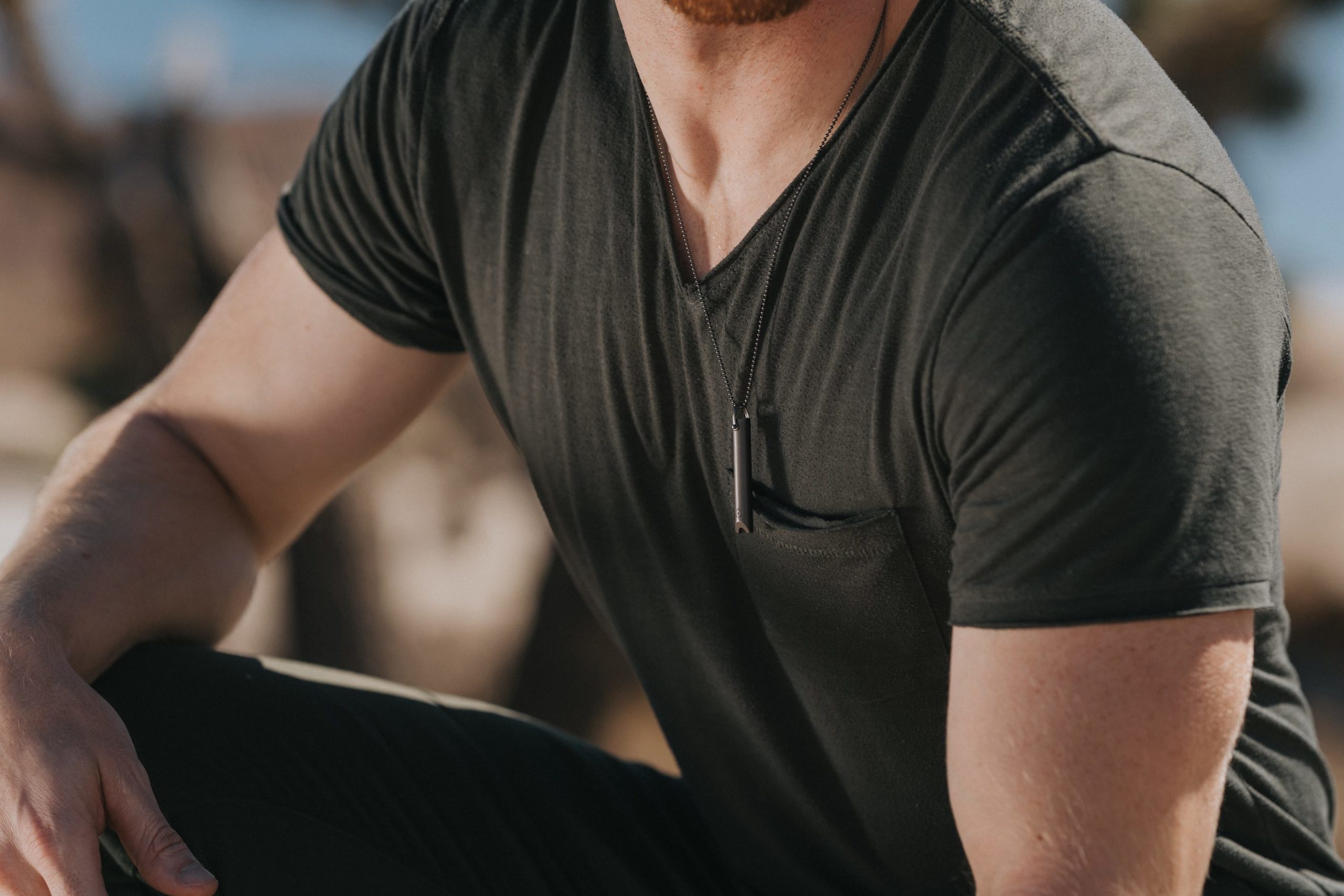 Komuso Design Photography Closeup of a muscular man wearing a black t shirt wearing a silver colored whistle around his neck