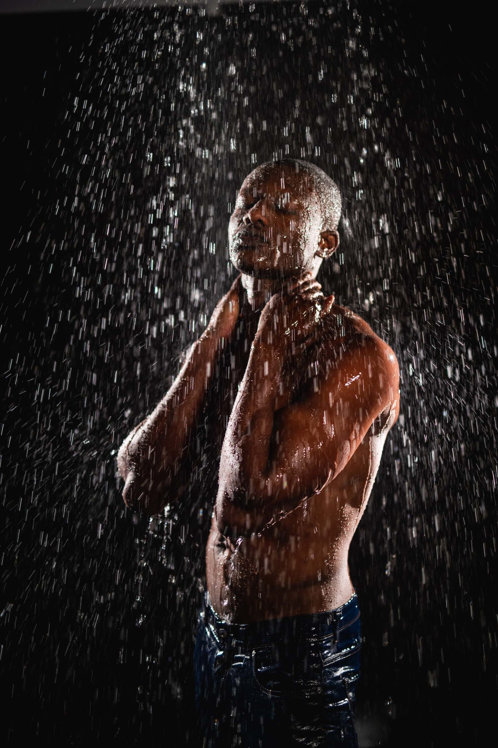 Crew Call Rain and Water Side profile of a man posing standing under a shower of water with eyes closed and soaked jeans