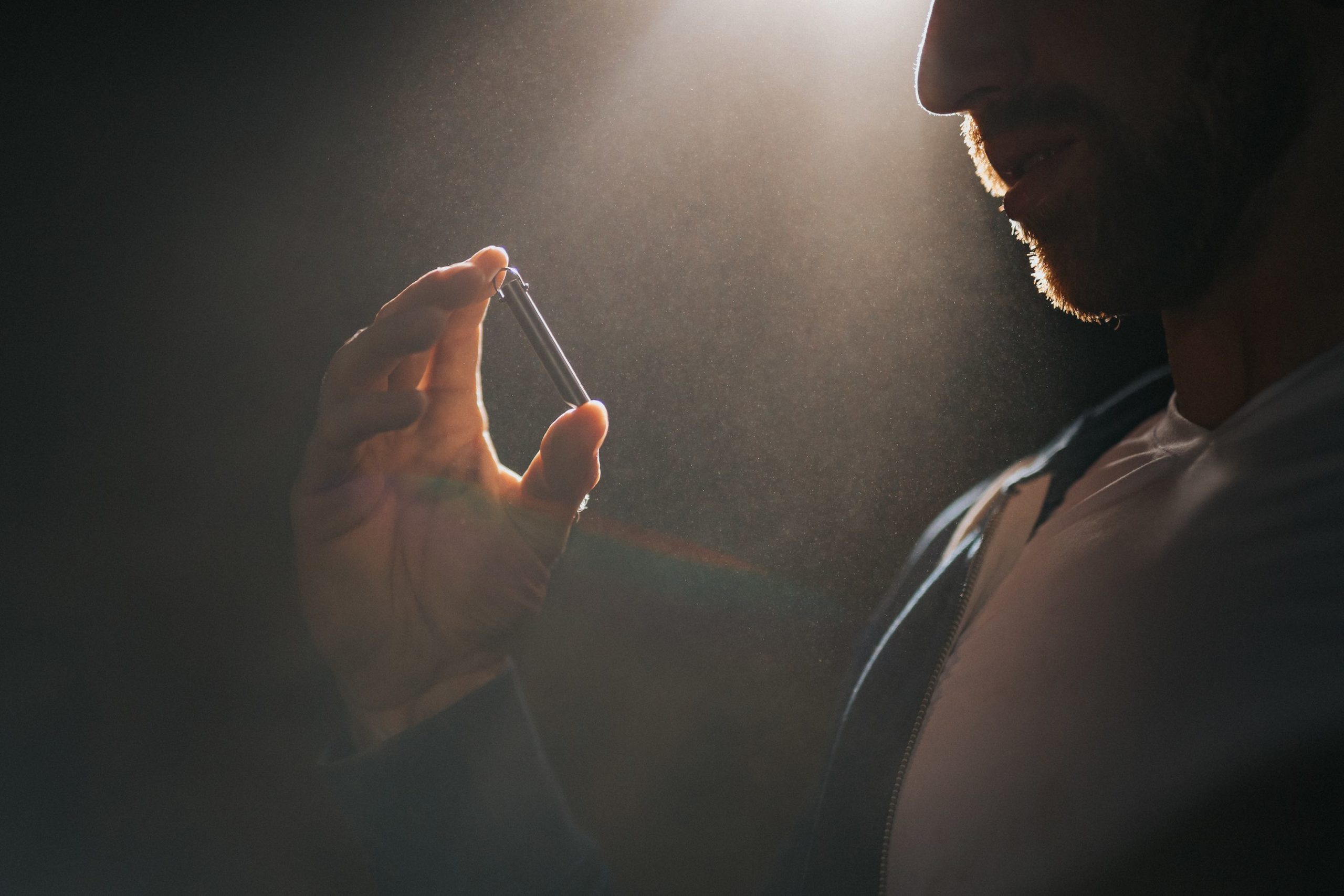 IU The Top 5 Proven Tips for Brand Building on Social Media Closeup of a bearded man in a dim light looking at a silver colored whistle he's holding in his hand