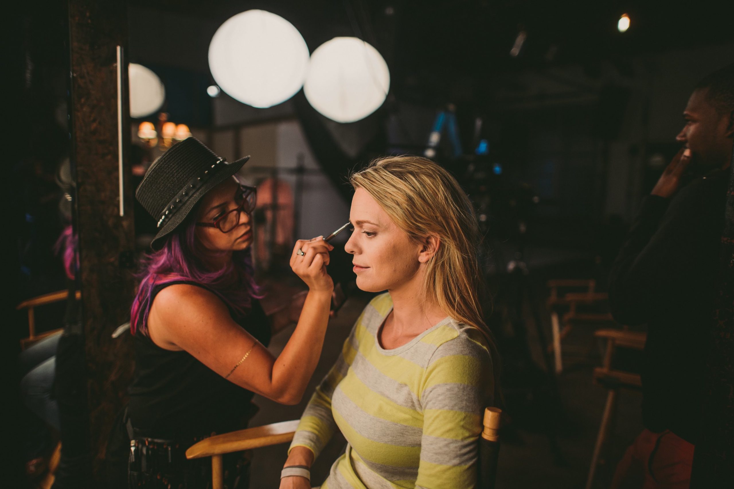 Side profile of woman getting makeup applied by a makeup artist