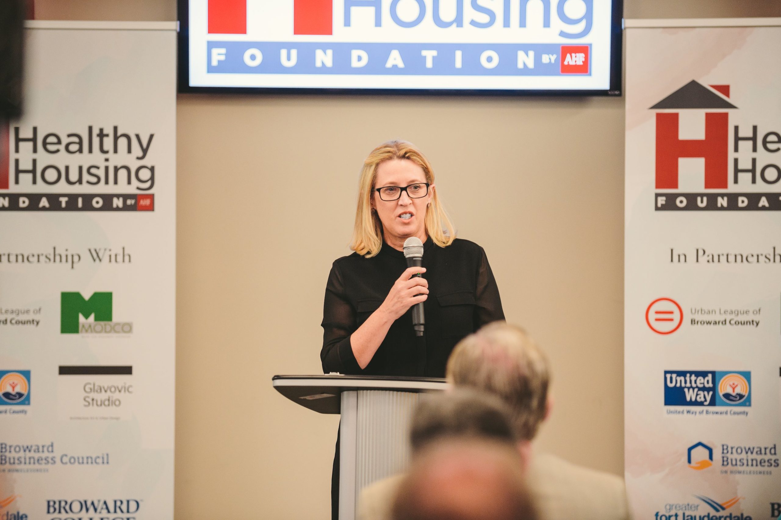 Woman speaking to audience at Healthy Housing Foundation event