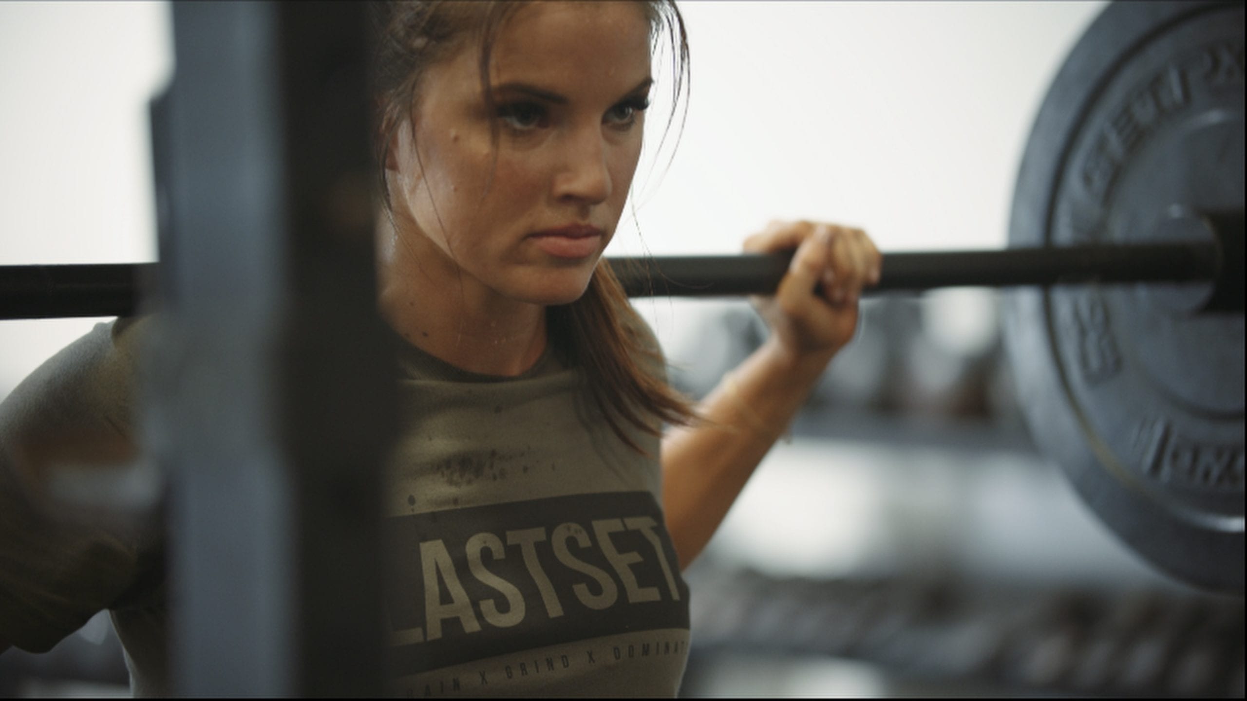 LastSet Co Closeup of woman wearing a gray t shirt lifting weight