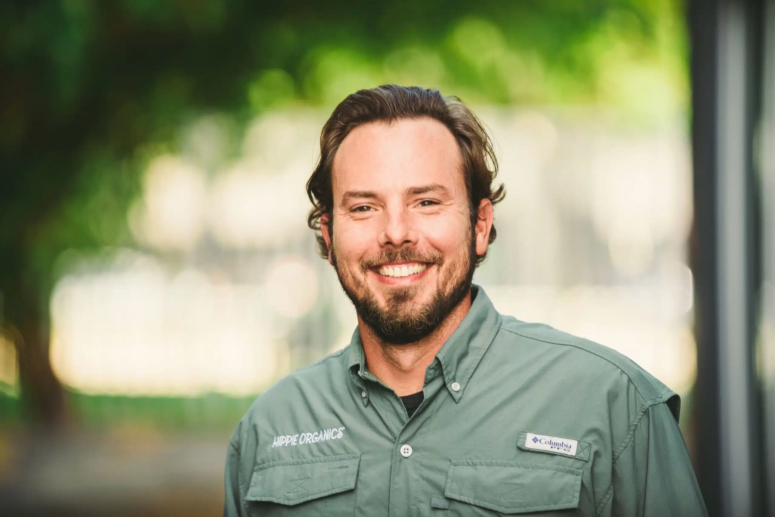 Hippie Organics by Alpine Fresh 15 Headshot of male Hippee Organics employee with brown short hair and beard wearing green uniform