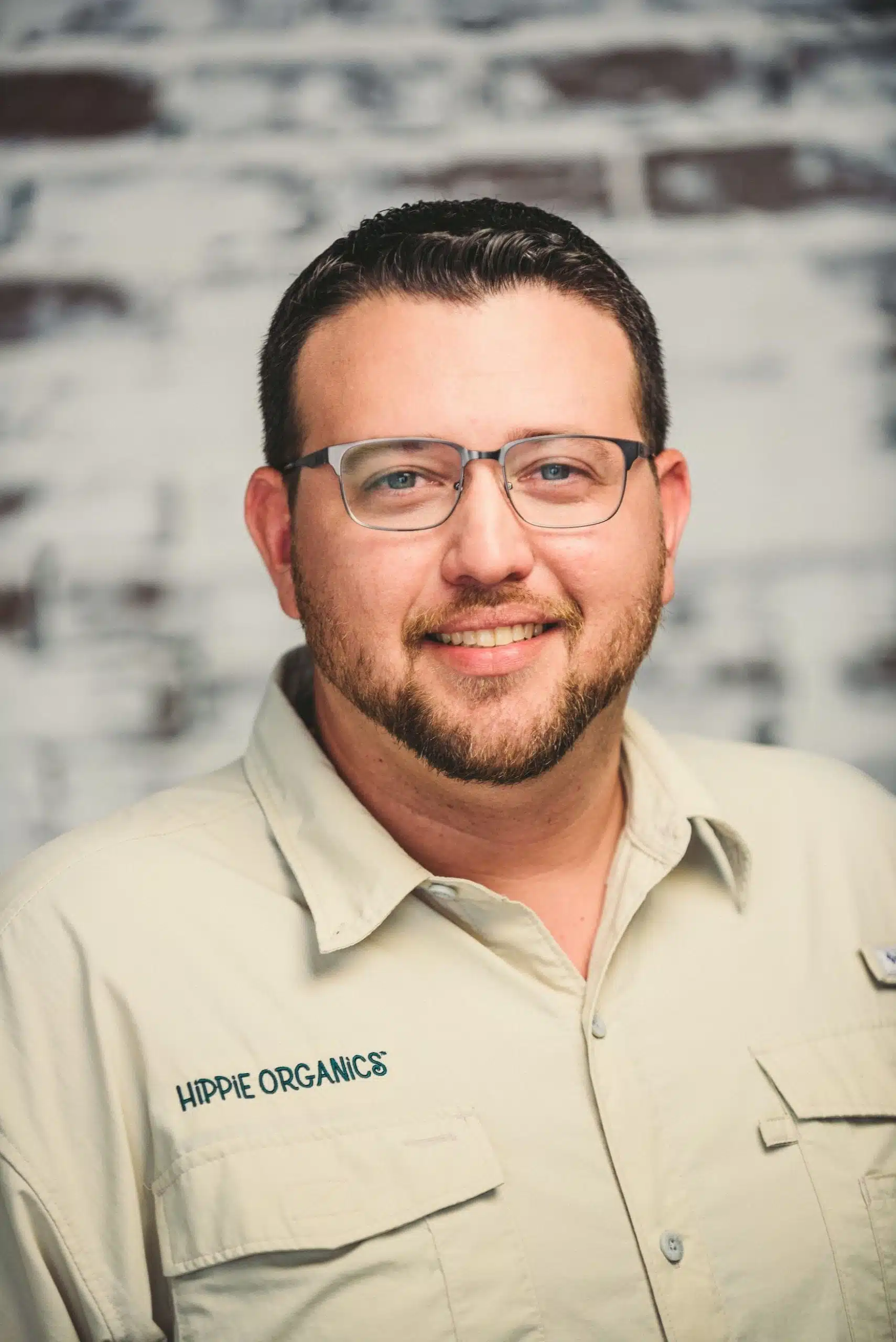 Hippie Organics by Alpine Fresh 18 Headshot of male Hippee Organics employee with short hair and beard wearing glasses wearing beige uniform